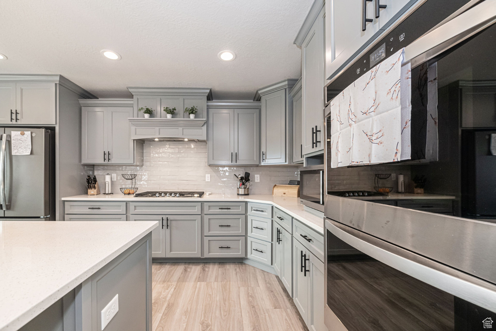Kitchen featuring gray cabinetry, decorative backsplash, and appliances with stainless steel finishes