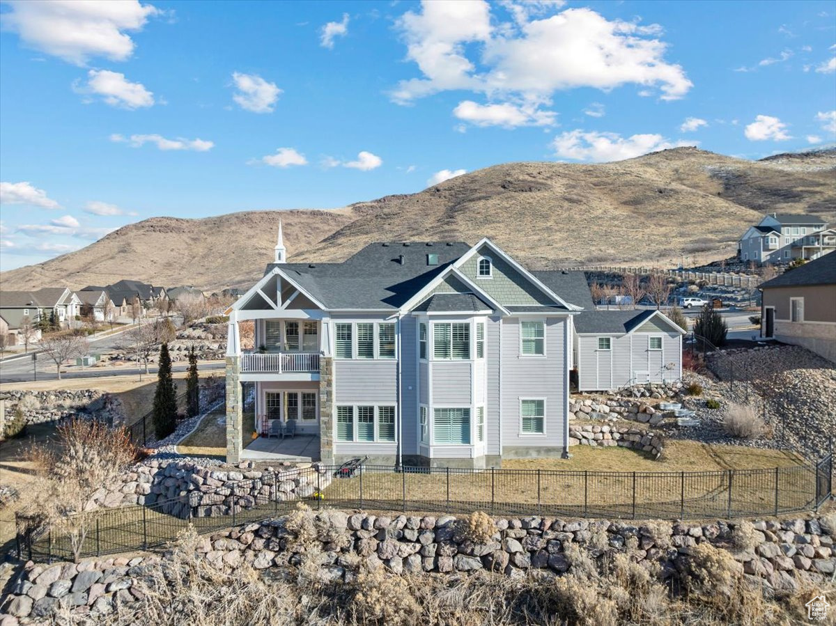 Back of property with a mountain view, a balcony, and a patio