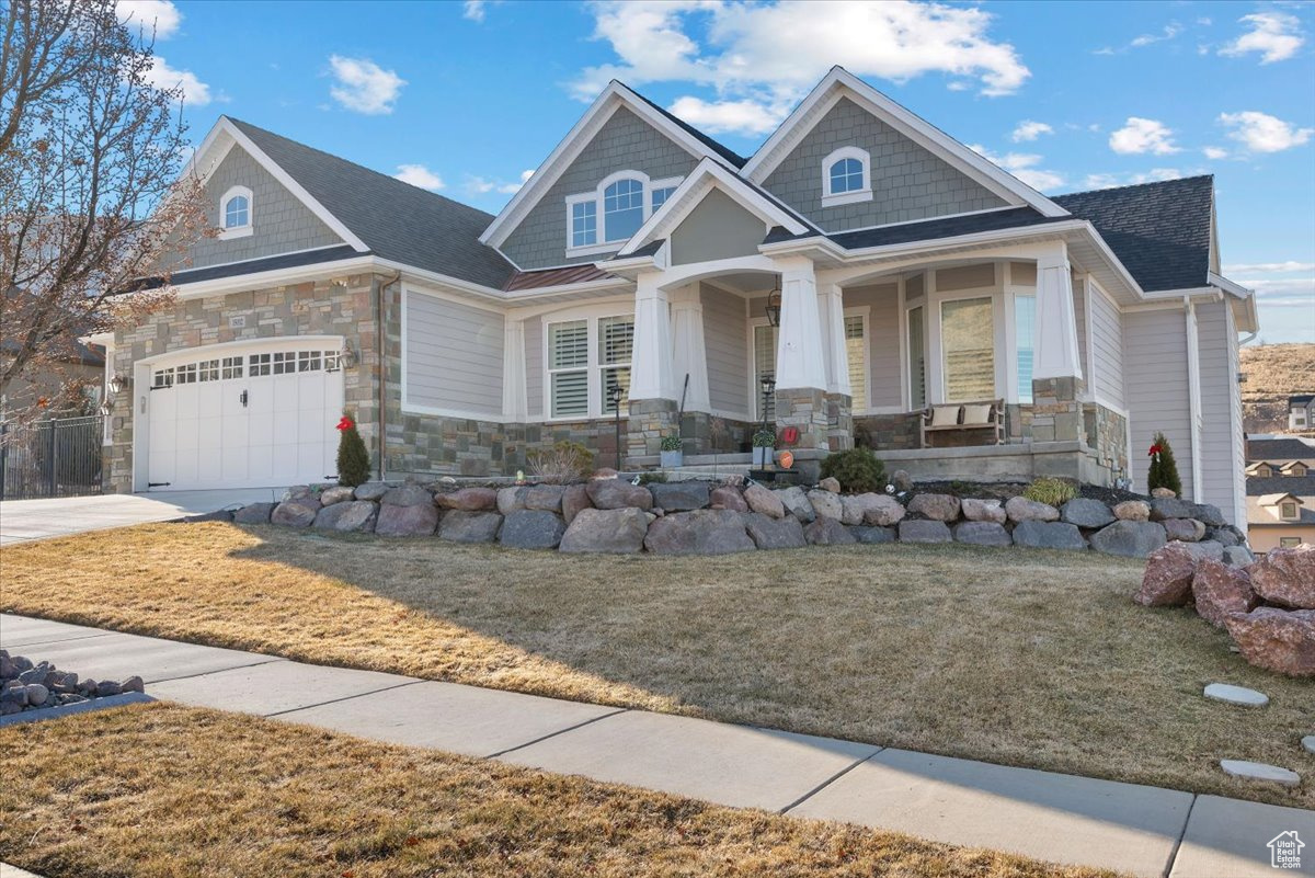 Craftsman inspired home with covered porch, a garage, and a front yard