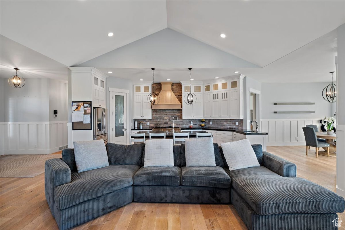 Living room with light hardwood / wood-style floors, sink, and high vaulted ceiling