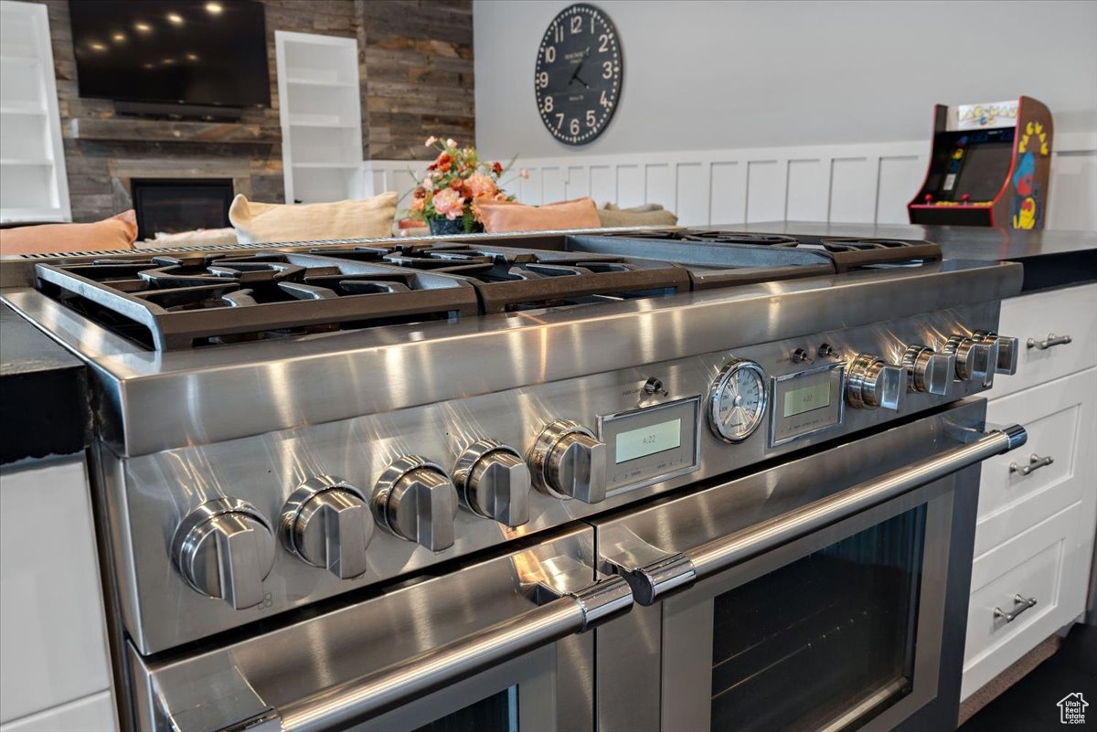 Details featuring white cabinetry, wood walls, and range with two ovens