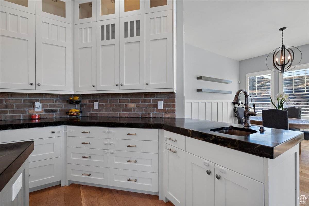 Kitchen featuring sink, white cabinets, pendant lighting, and an inviting chandelier