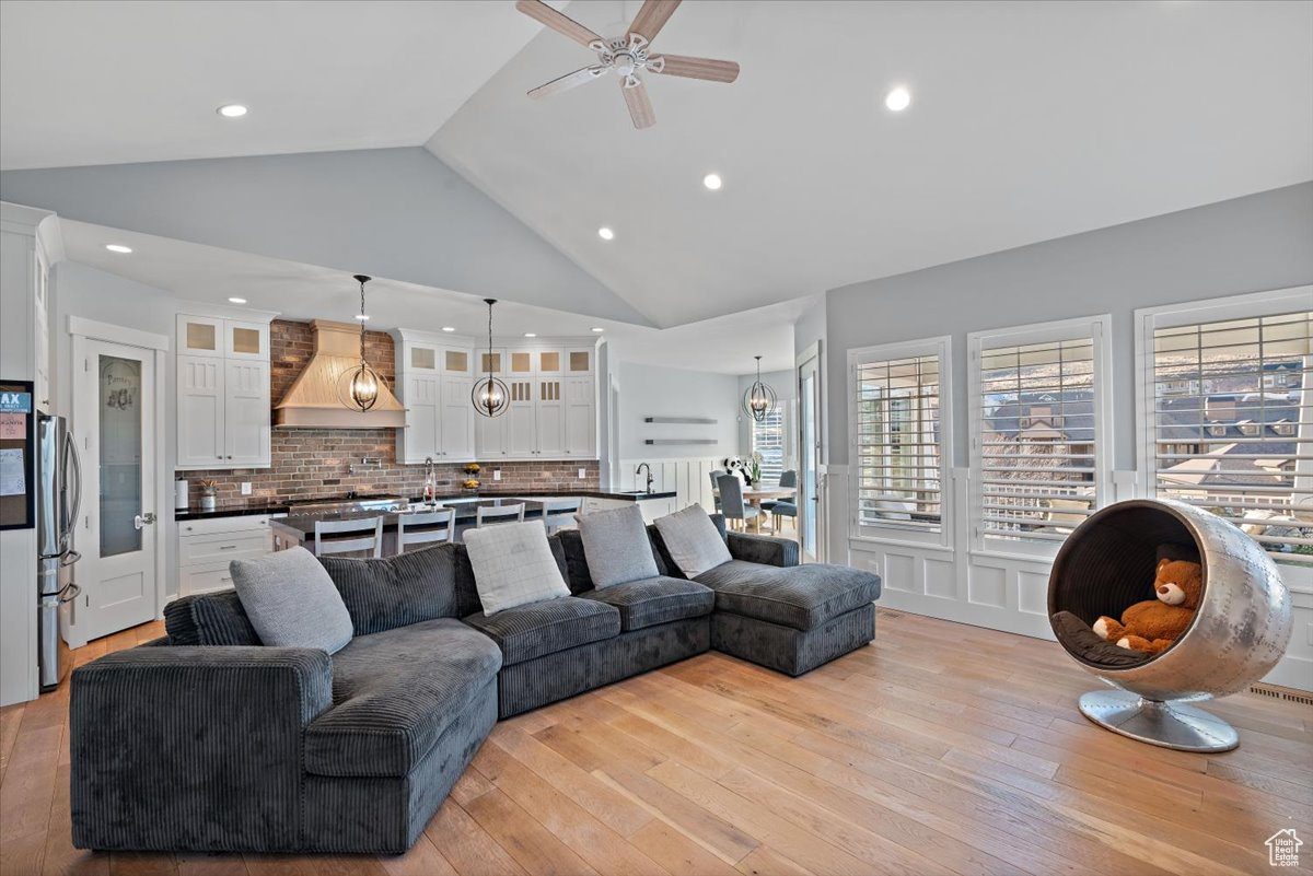 Living room with ceiling fan, light hardwood / wood-style flooring, and high vaulted ceiling