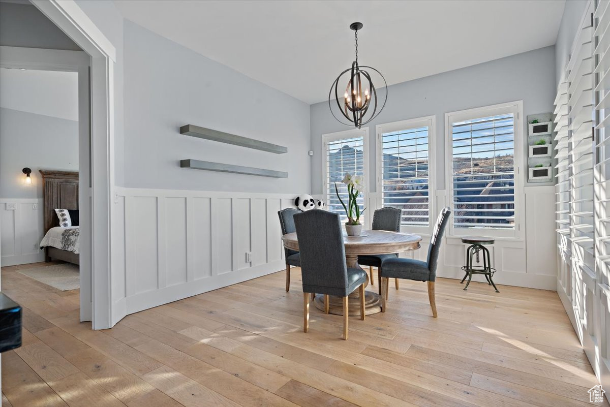 Dining room with light hardwood / wood-style floors and a notable chandelier