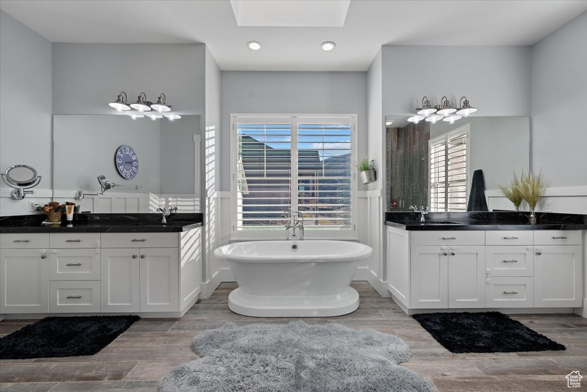 Bathroom with a bathing tub, vanity, and a skylight