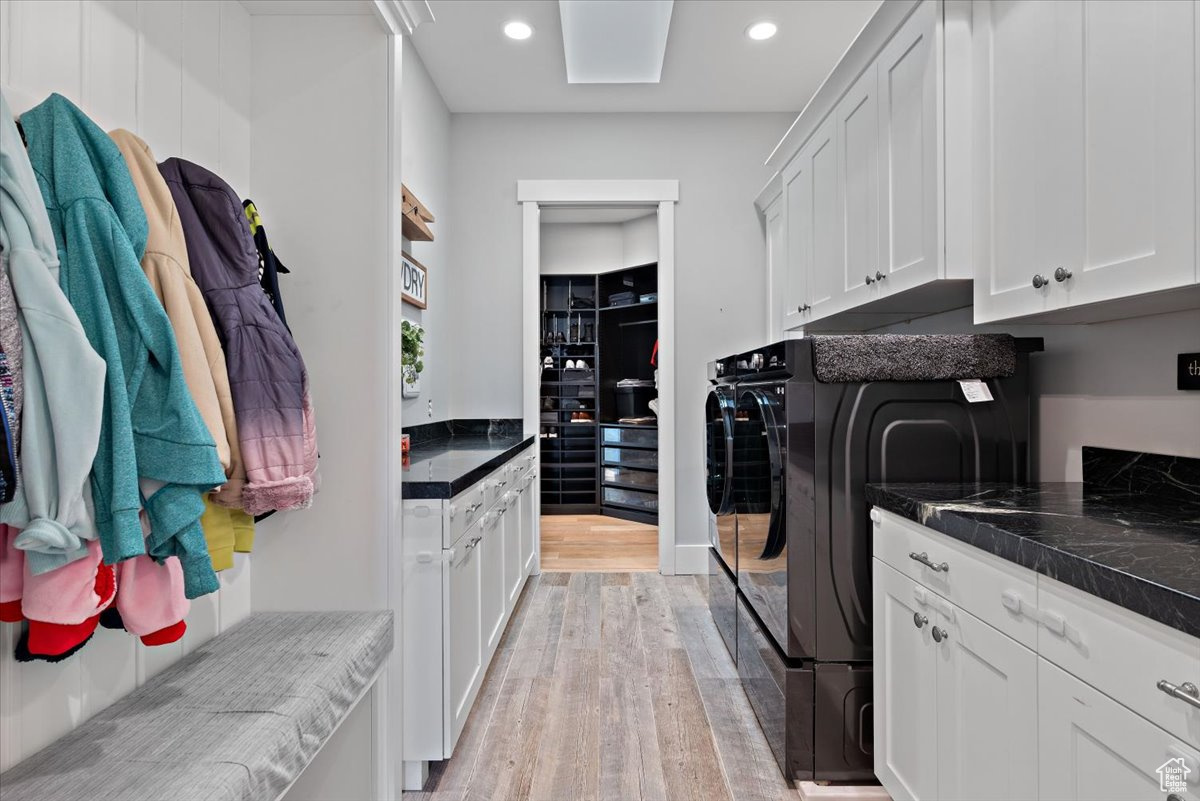 Laundry area with cabinets, light hardwood / wood-style floors, and washing machine and dryer