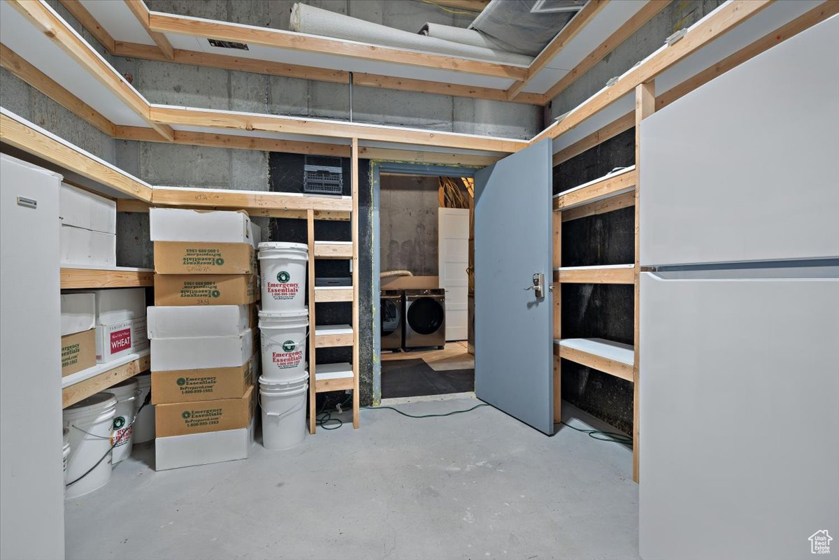 Basement with washing machine and clothes dryer and white refrigerator