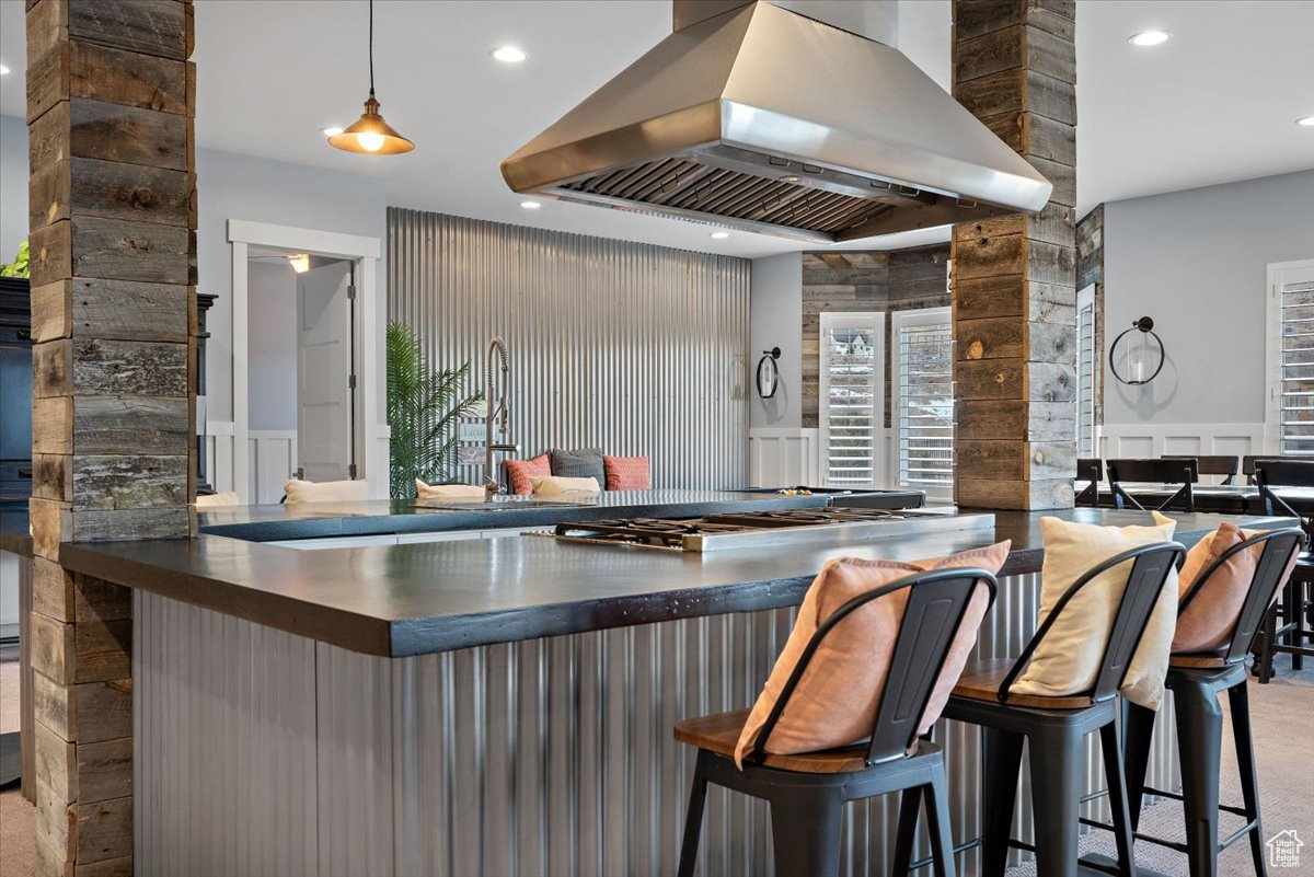 Kitchen featuring a breakfast bar, pendant lighting, and range hood