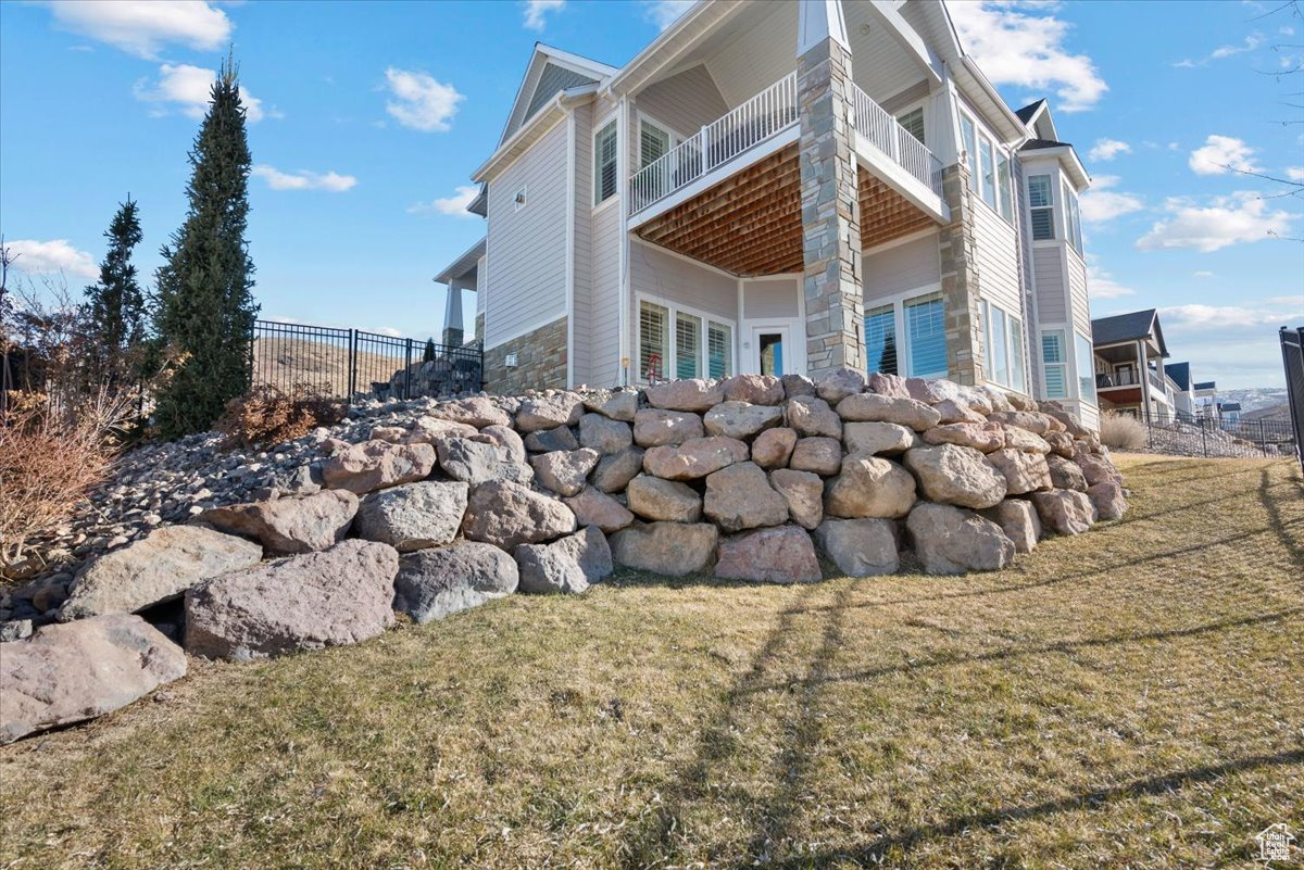 View of property exterior with a balcony and a yard