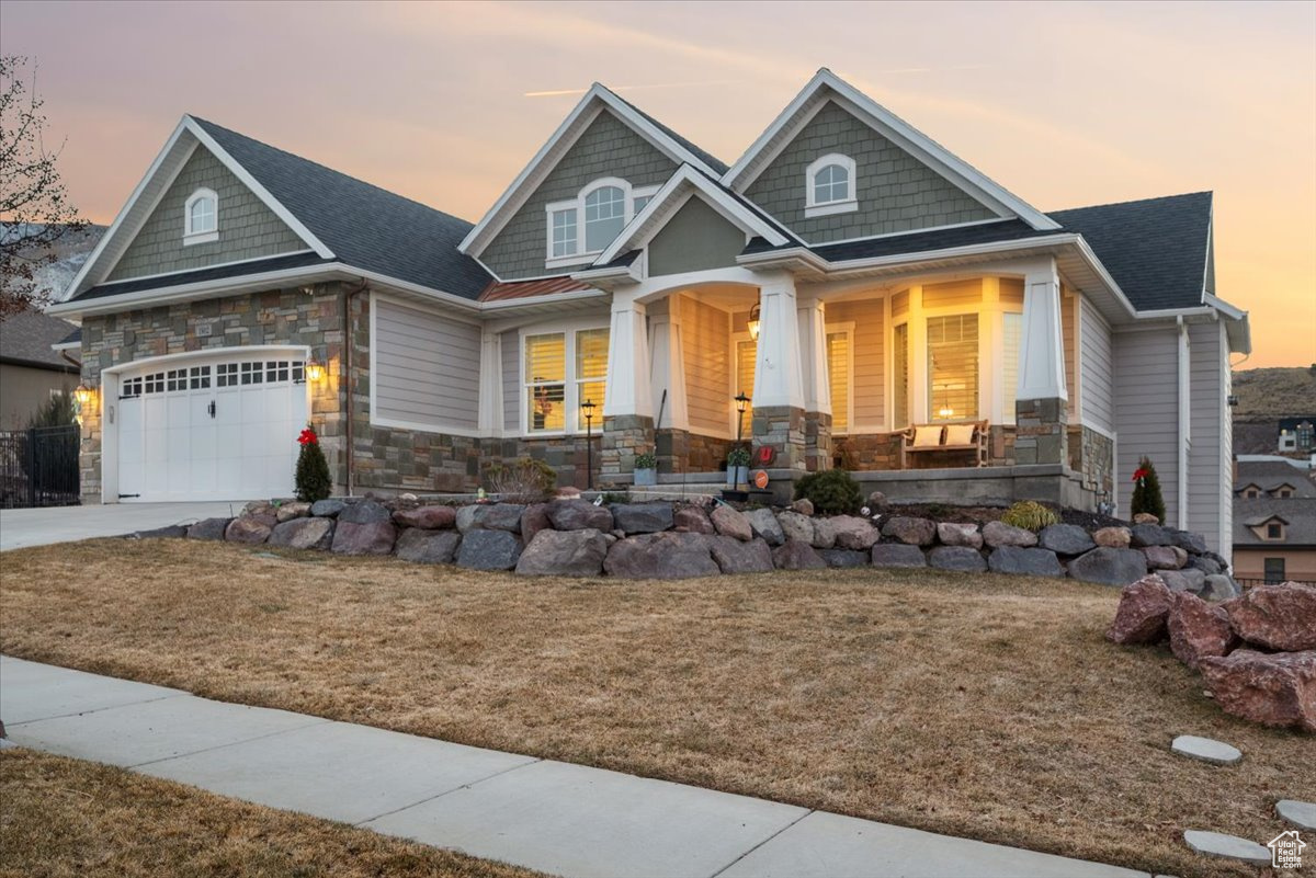 Craftsman inspired home featuring a yard, covered porch, and a garage