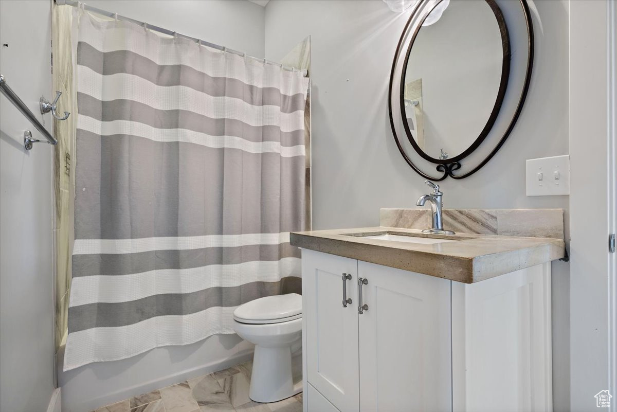 Full bathroom featuring vanity, toilet, and shower / bathtub combination with curtain