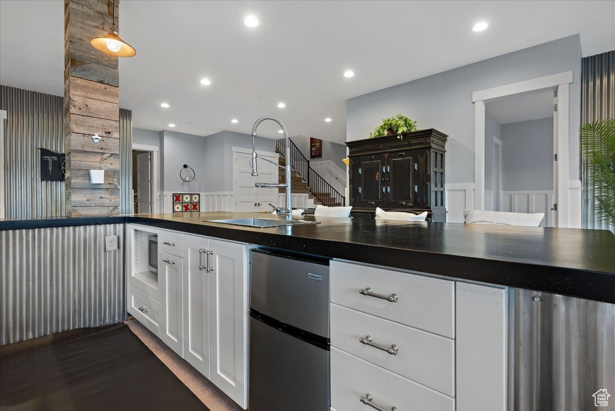 Kitchen with white cabinetry, sink, and fridge