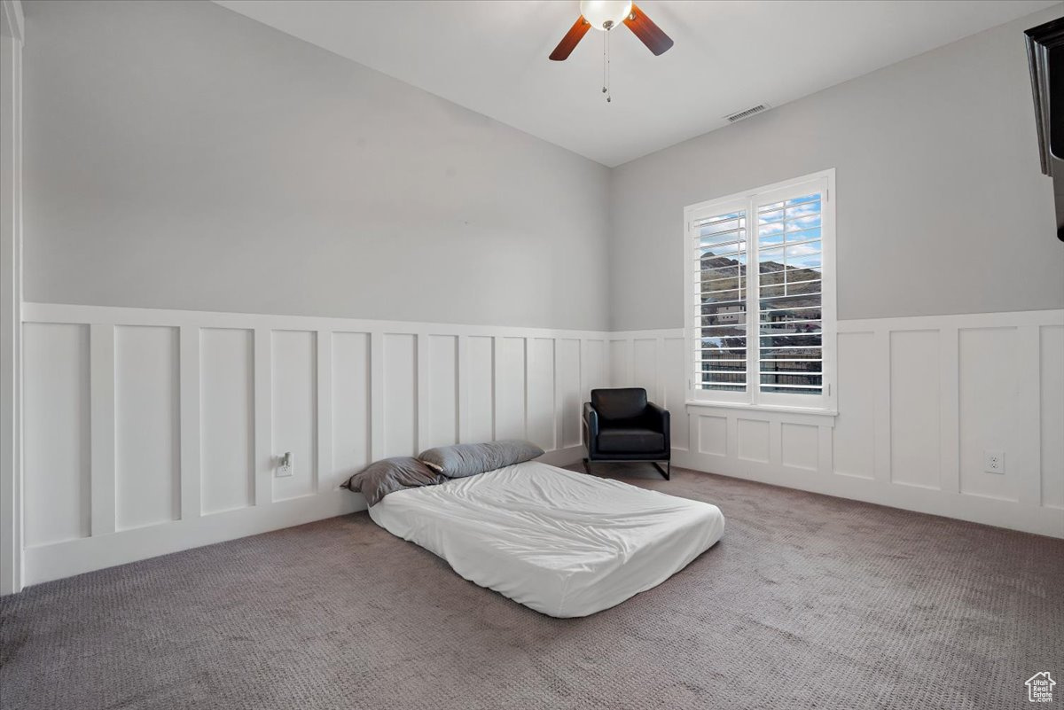 Bedroom with ceiling fan and light carpet