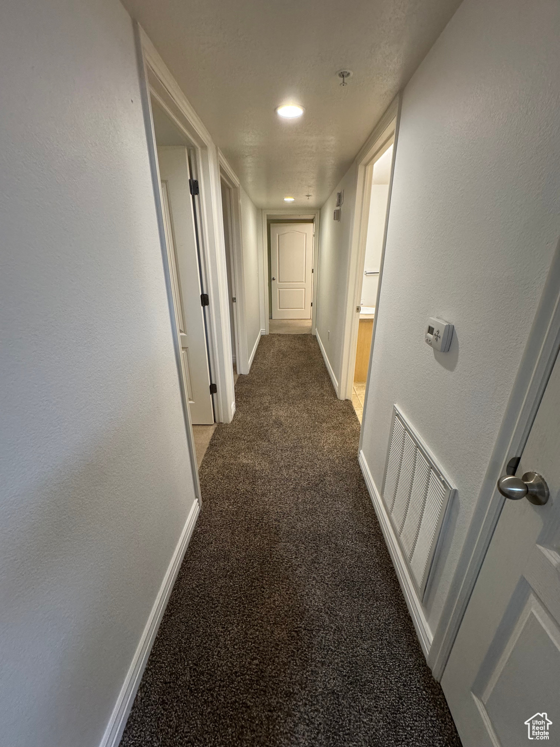 Hallway featuring dark colored carpet