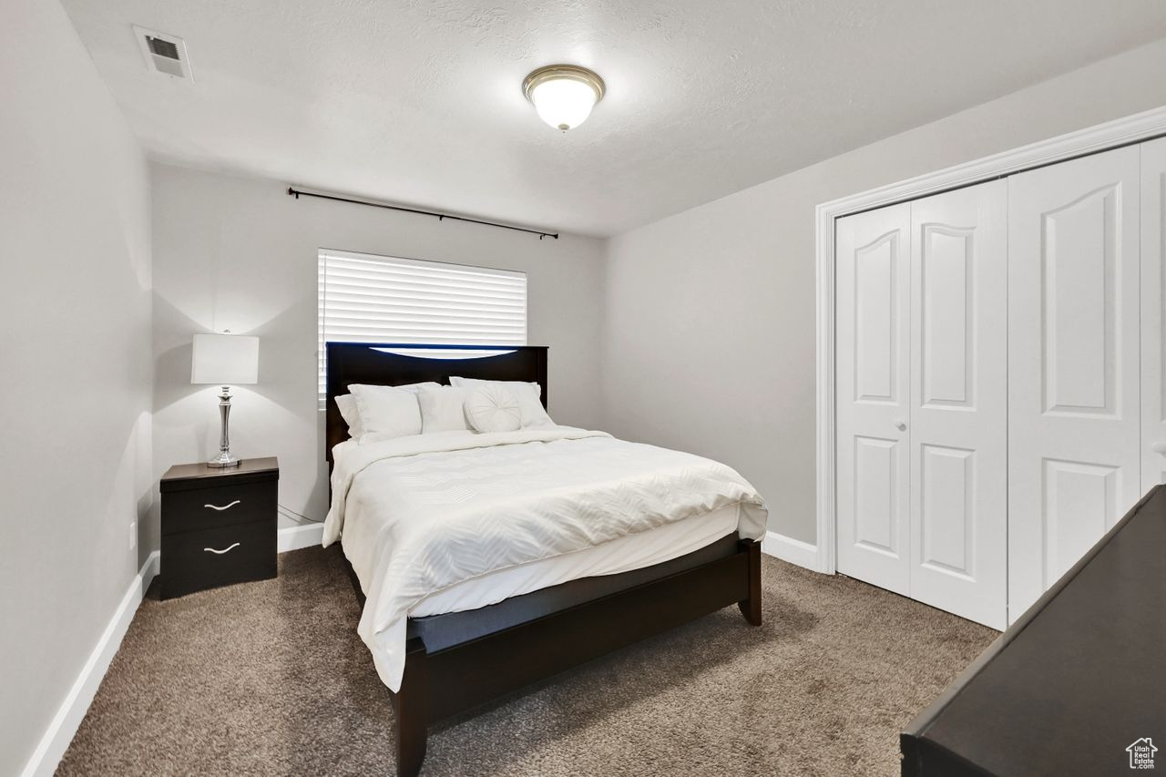 Carpeted bedroom featuring a textured ceiling and a closet