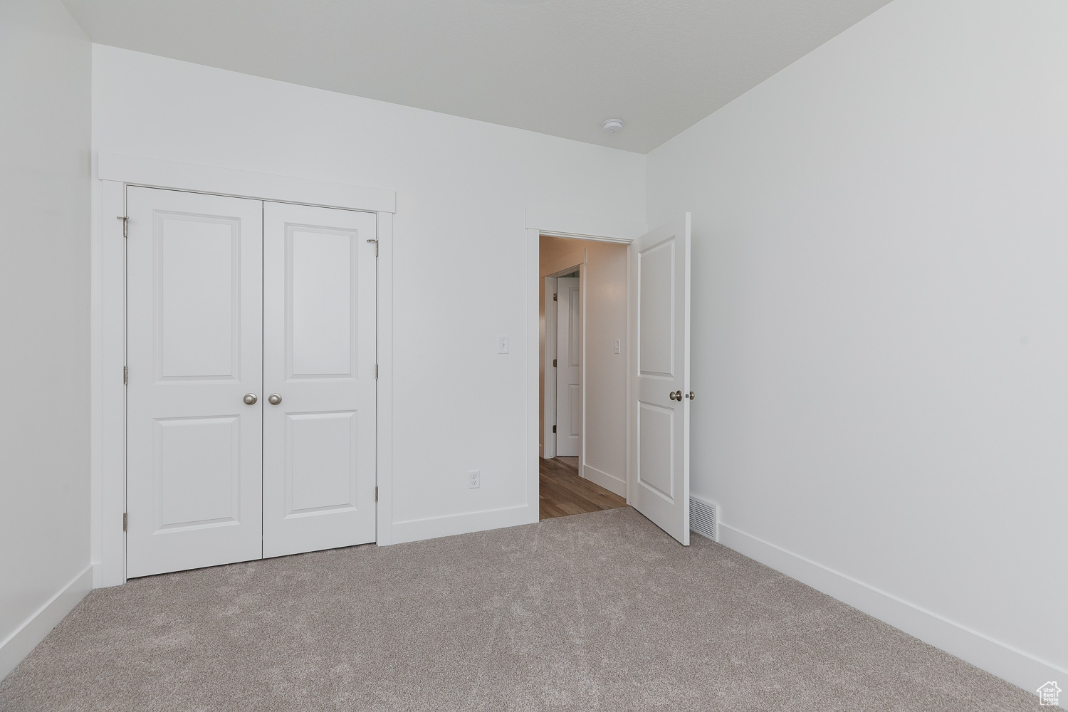 Unfurnished bedroom with light carpet and a closet