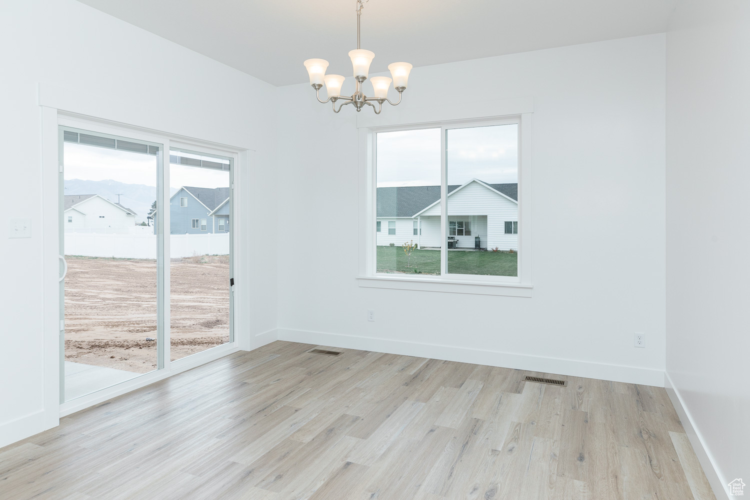 Unfurnished dining area with a chandelier, light hardwood / wood-style floors, and plenty of natural light