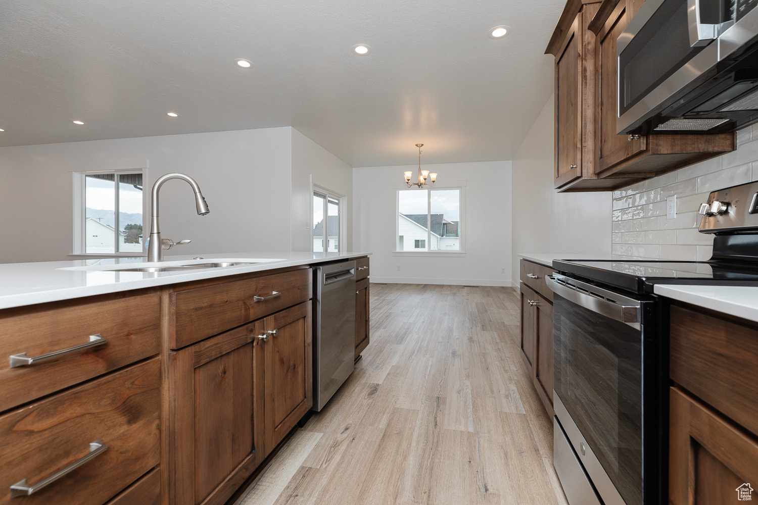 Kitchen featuring an inviting chandelier, sink, light wood-type flooring, a wealth of natural light, and stainless steel appliances