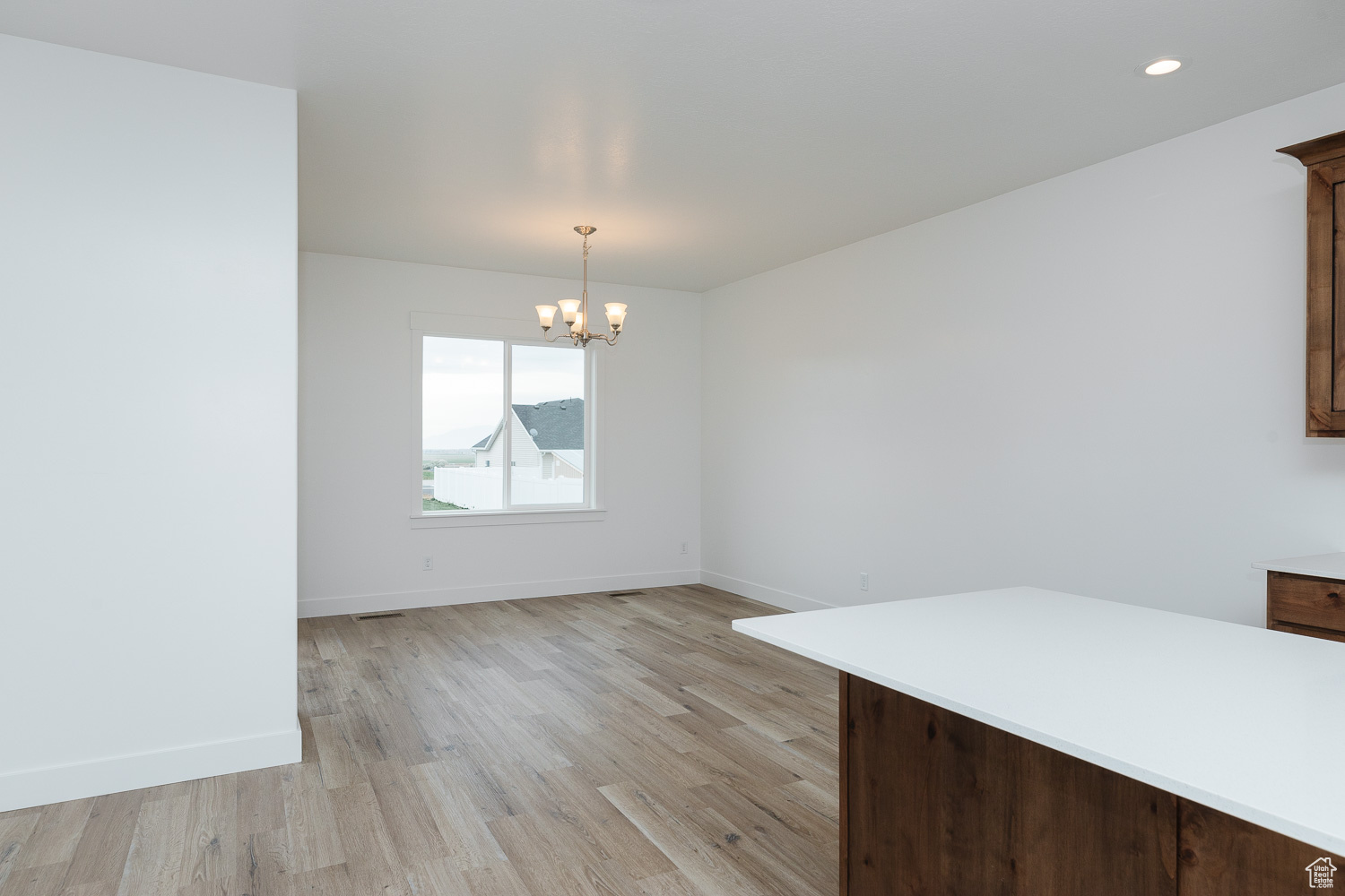Unfurnished dining area featuring light wood-type flooring and an inviting chandelier