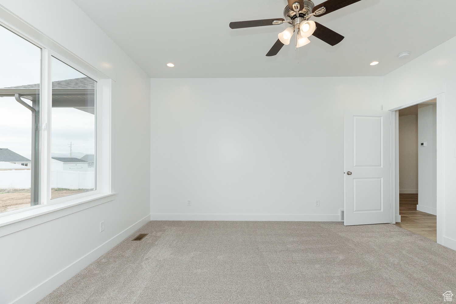 Unfurnished room featuring ceiling fan and light carpet