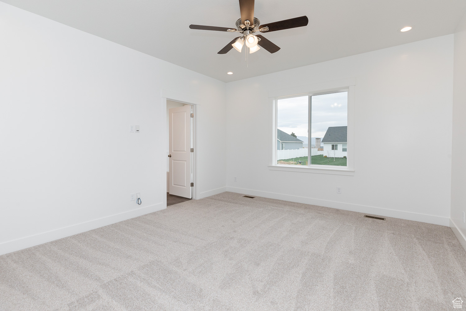 Carpeted empty room featuring ceiling fan