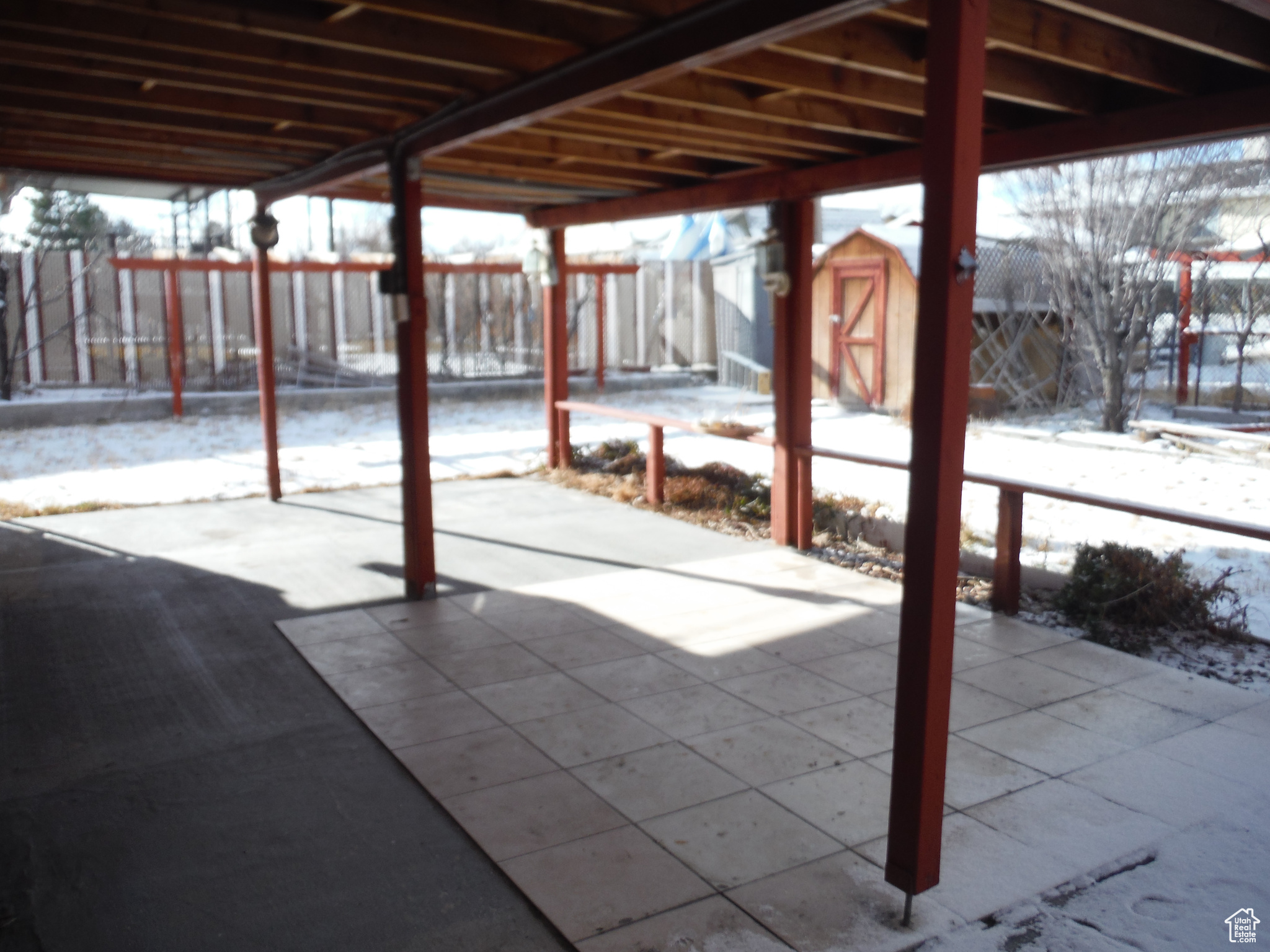 Snow covered patio featuring a storage shed