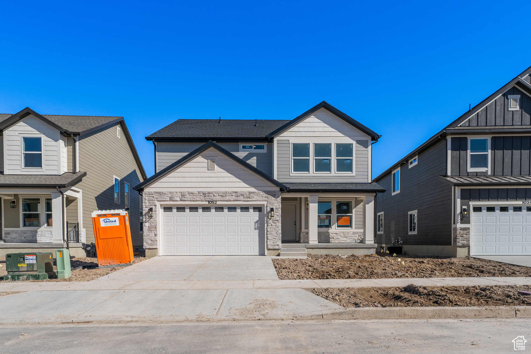 View of front of property featuring board and batten siding, concrete driveway, a garage, and stone siding