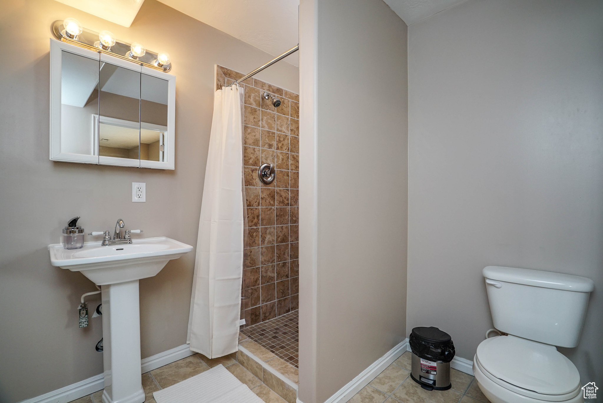 Bathroom featuring tile patterned flooring, toilet, curtained shower, and sink