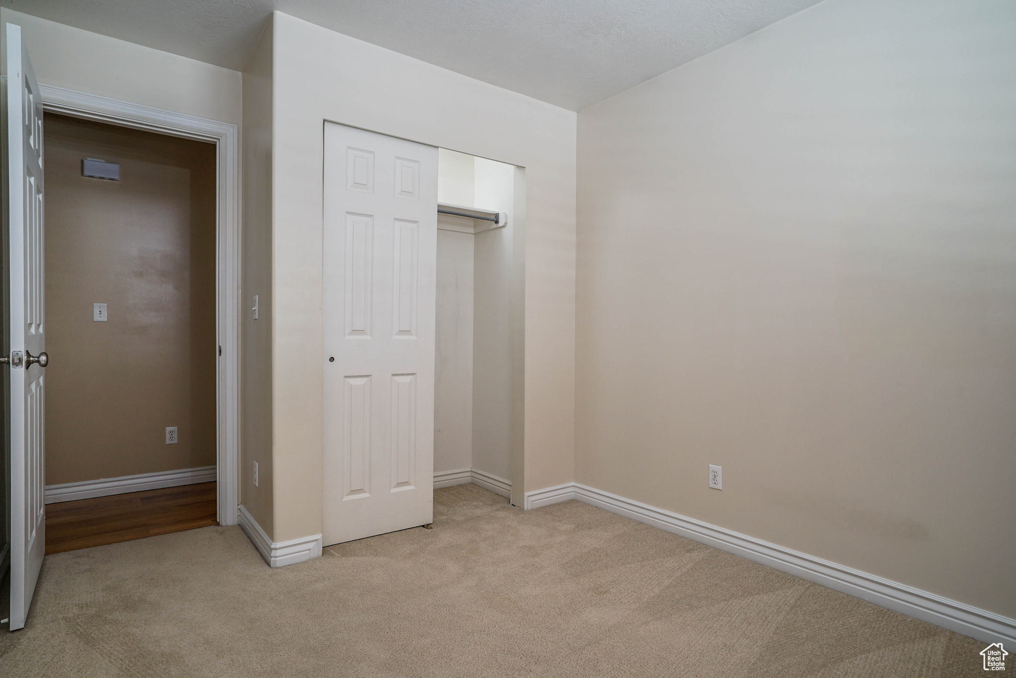Unfurnished bedroom with light carpet and a closet