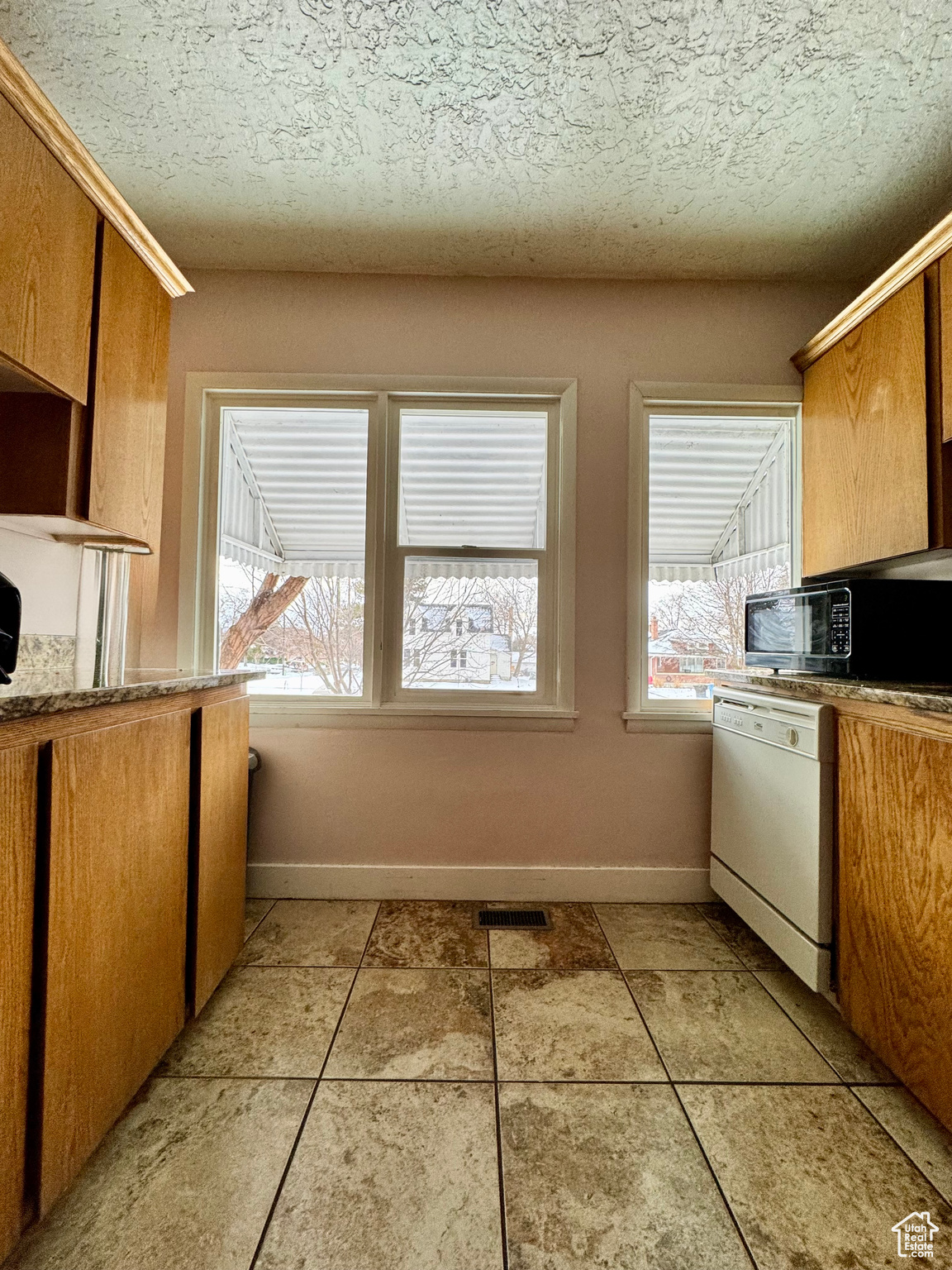 Kitchen with baseboards, visible vents, white dishwasher, a textured ceiling, and black microwave