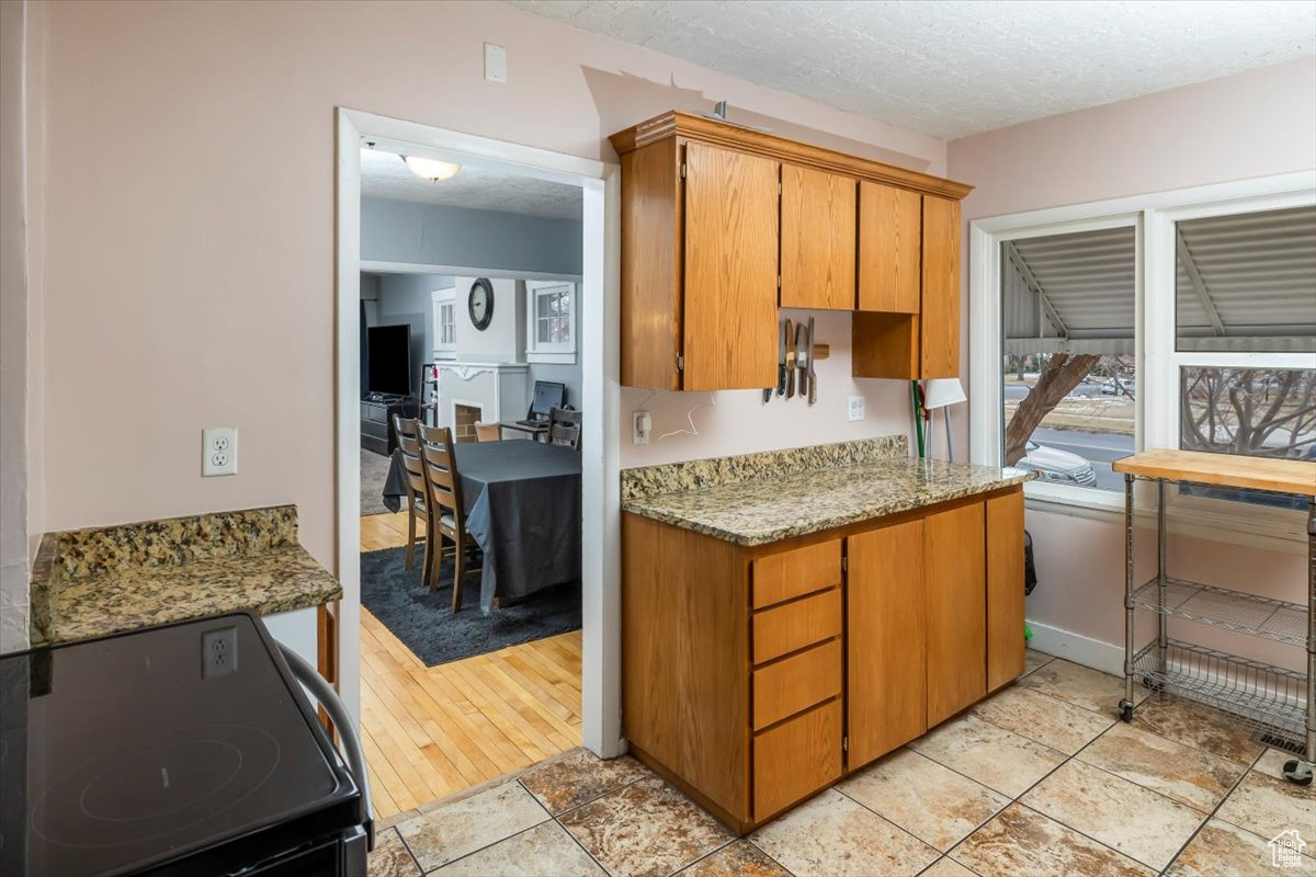 Kitchen featuring stove, a textured ceiling, and light stone counters