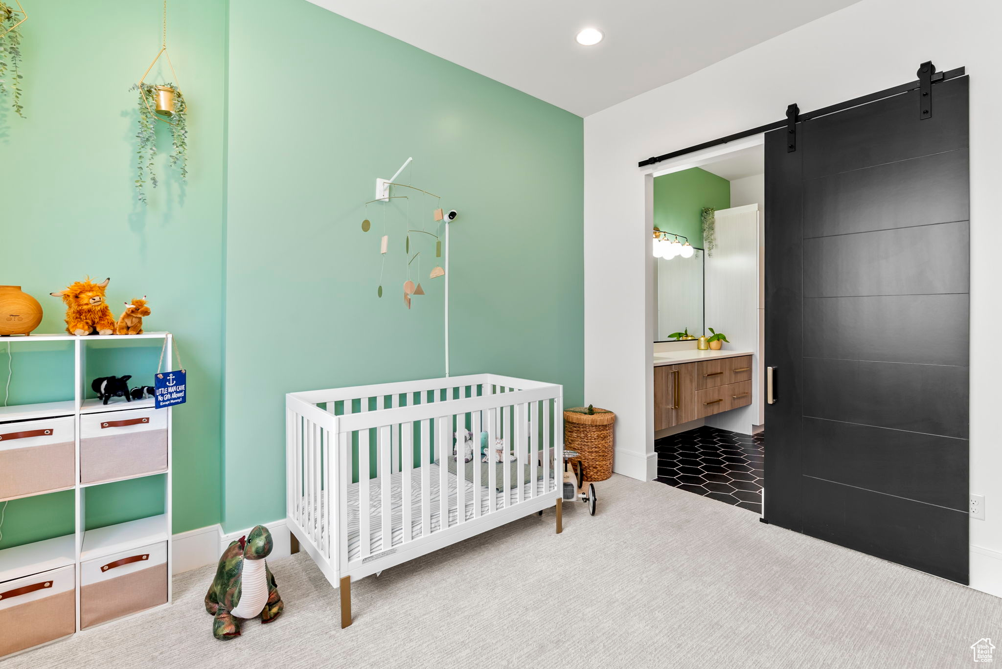 Carpeted bedroom with a barn door, ensuite bathroom, and a nursery area