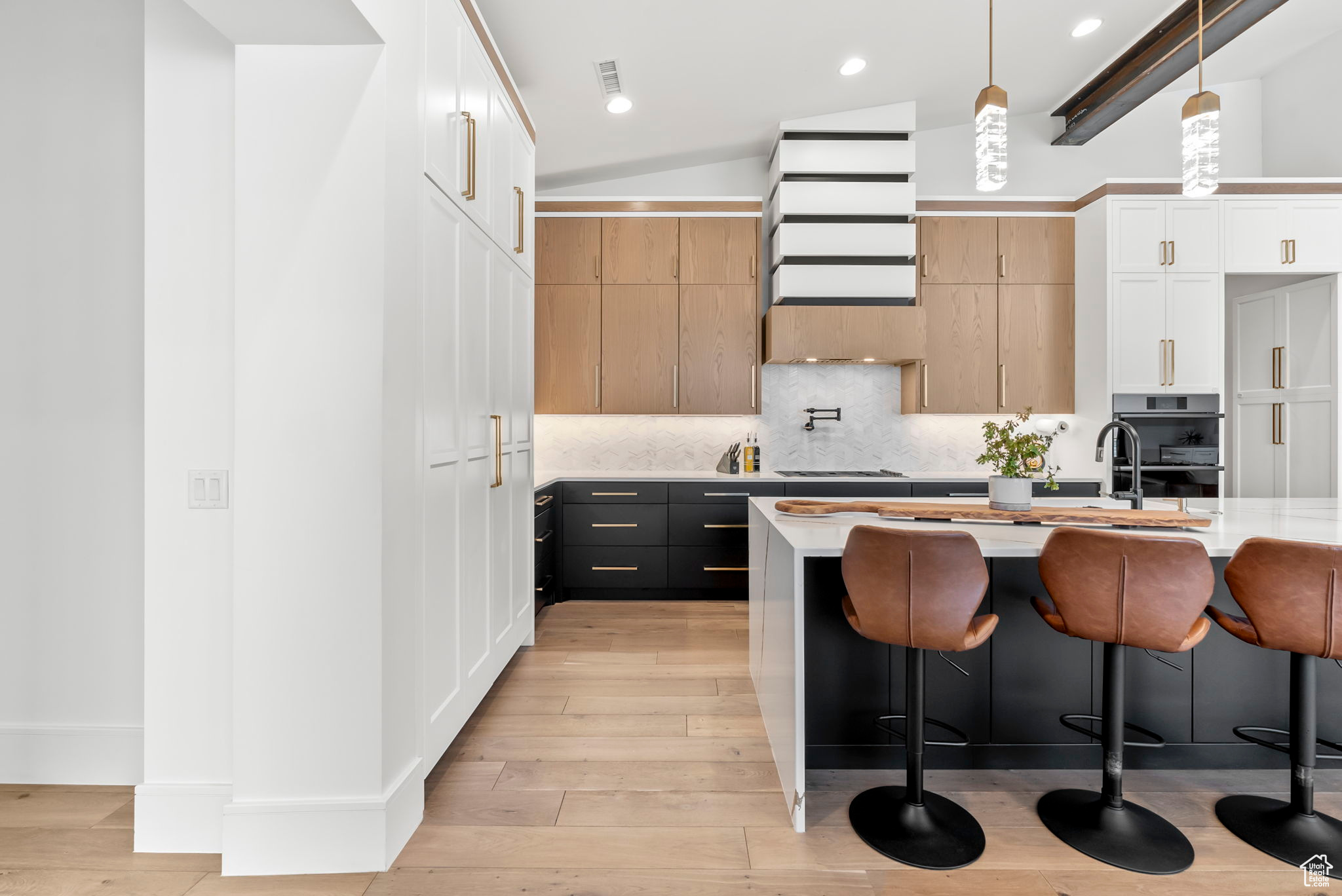 Kitchen featuring a center island, vaulted ceiling with beams, light hardwood / wood-style floors, white cabinetry, and hanging light fixtures