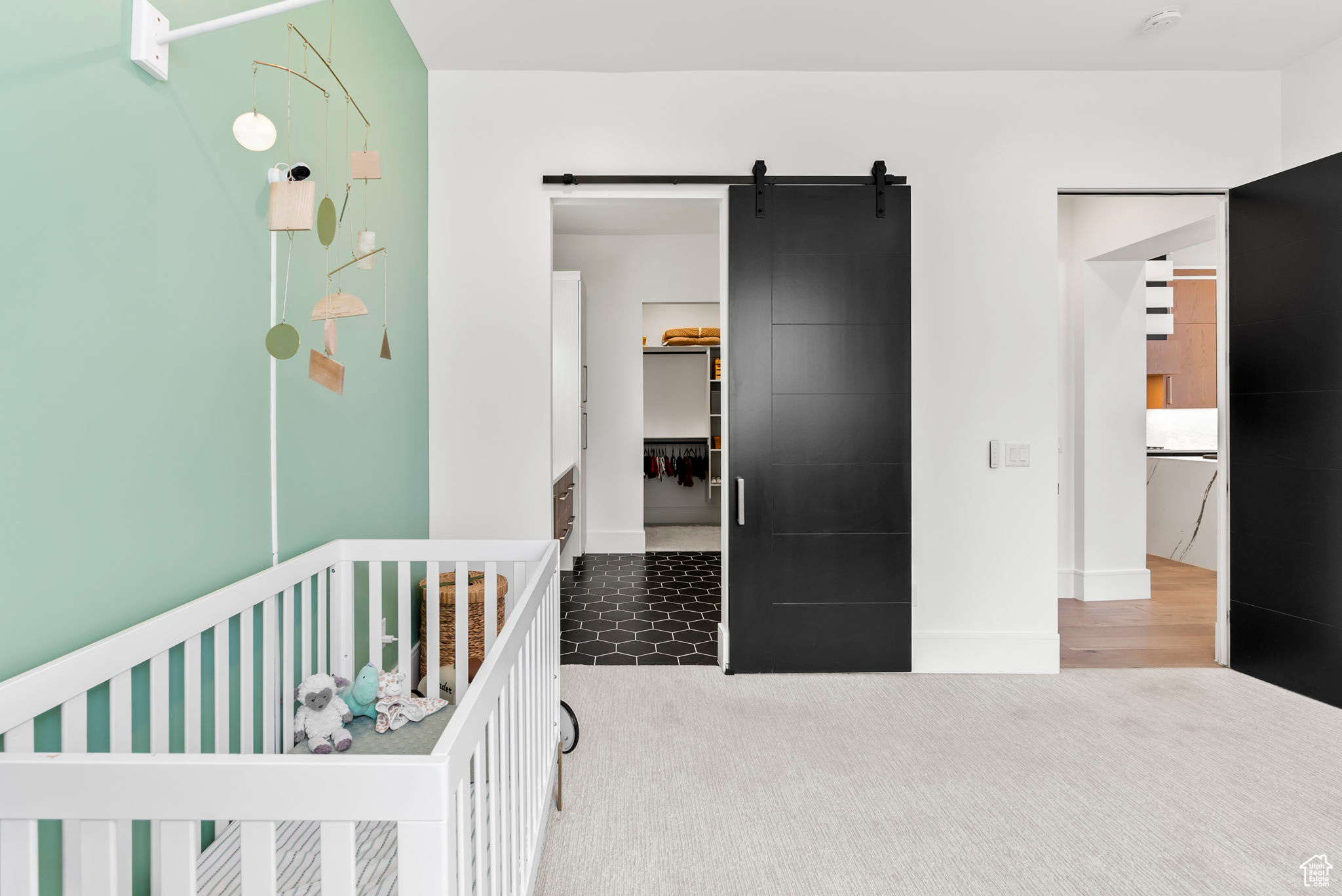 Bedroom featuring a barn door and a nursery area