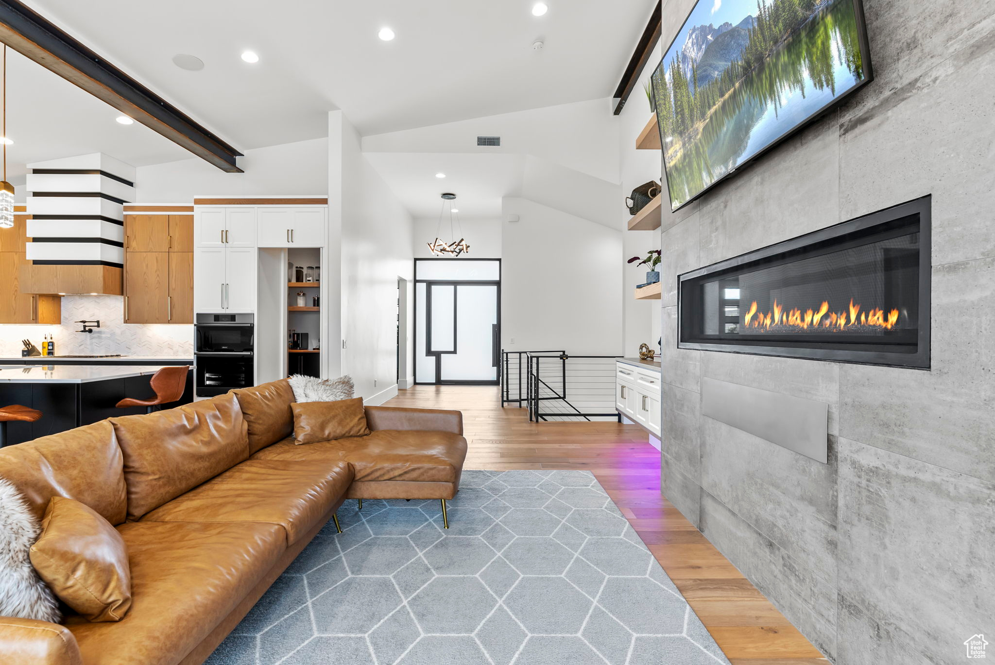 Living room featuring a tiled fireplace, wood-type flooring, and vaulted ceiling with beams