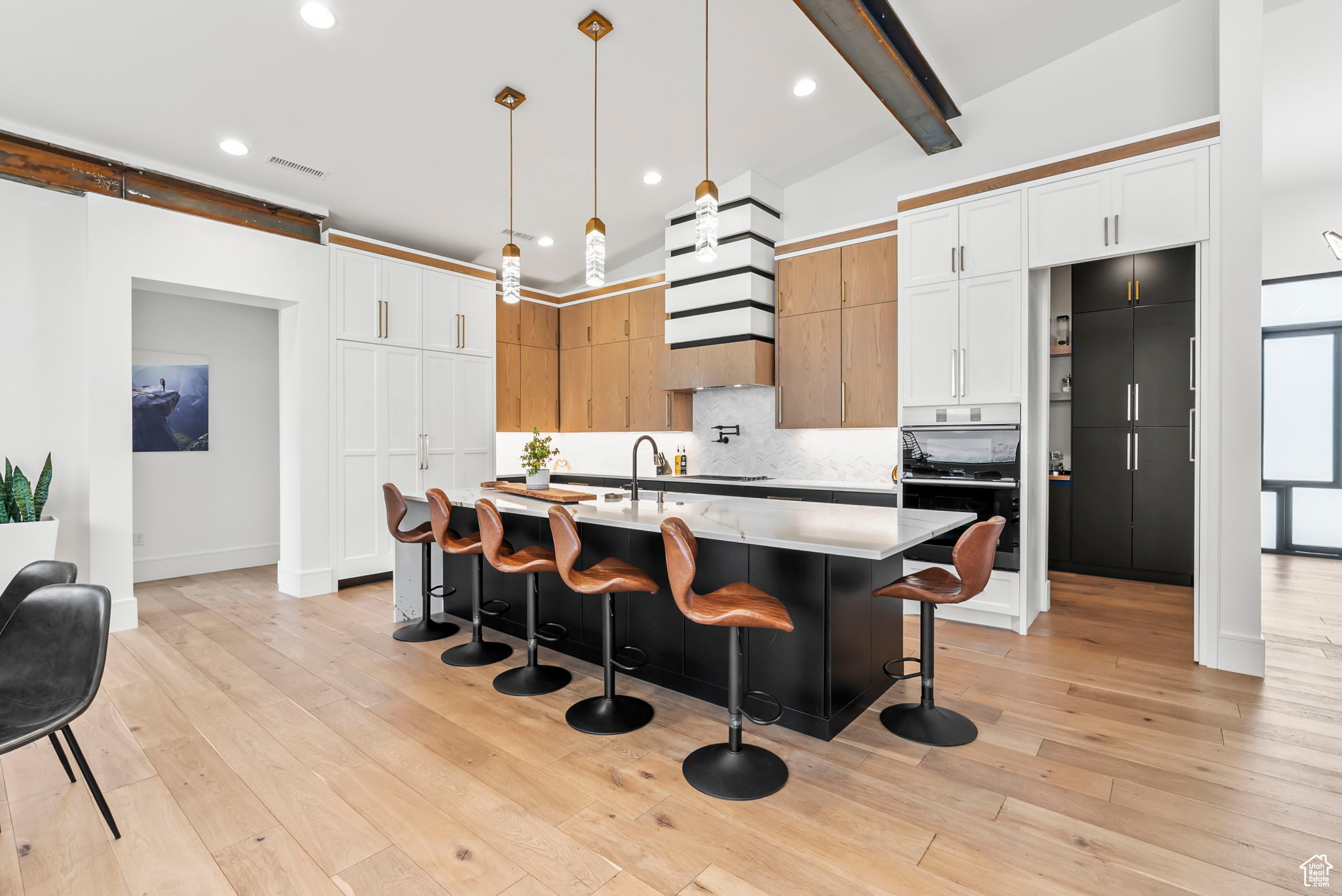 Kitchen with pendant lighting, a kitchen island with sink, a kitchen breakfast bar, light wood-type flooring, and white cabinetry