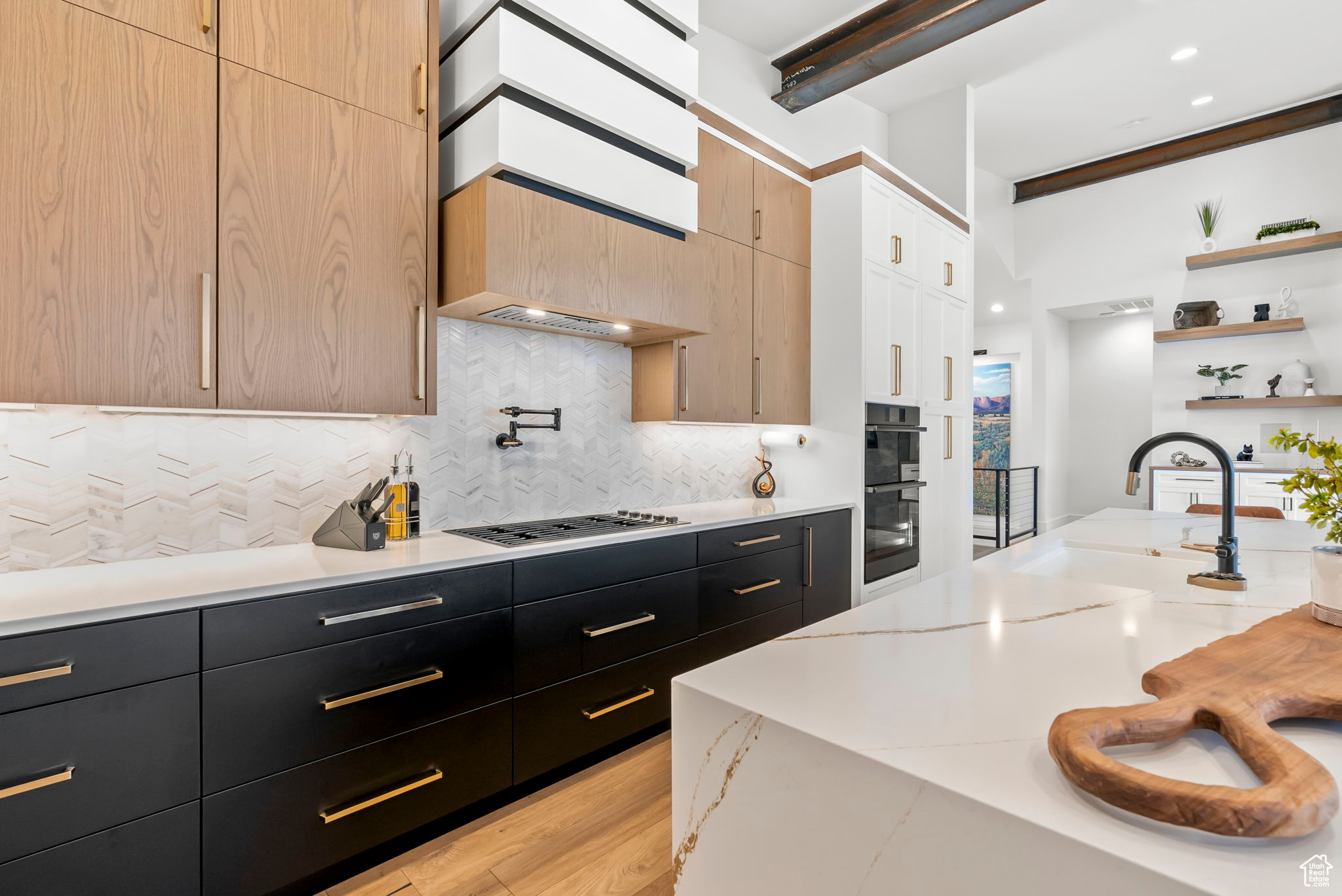 Kitchen featuring sink, double wall oven, light stone countertops, light brown cabinetry, and tasteful backsplash