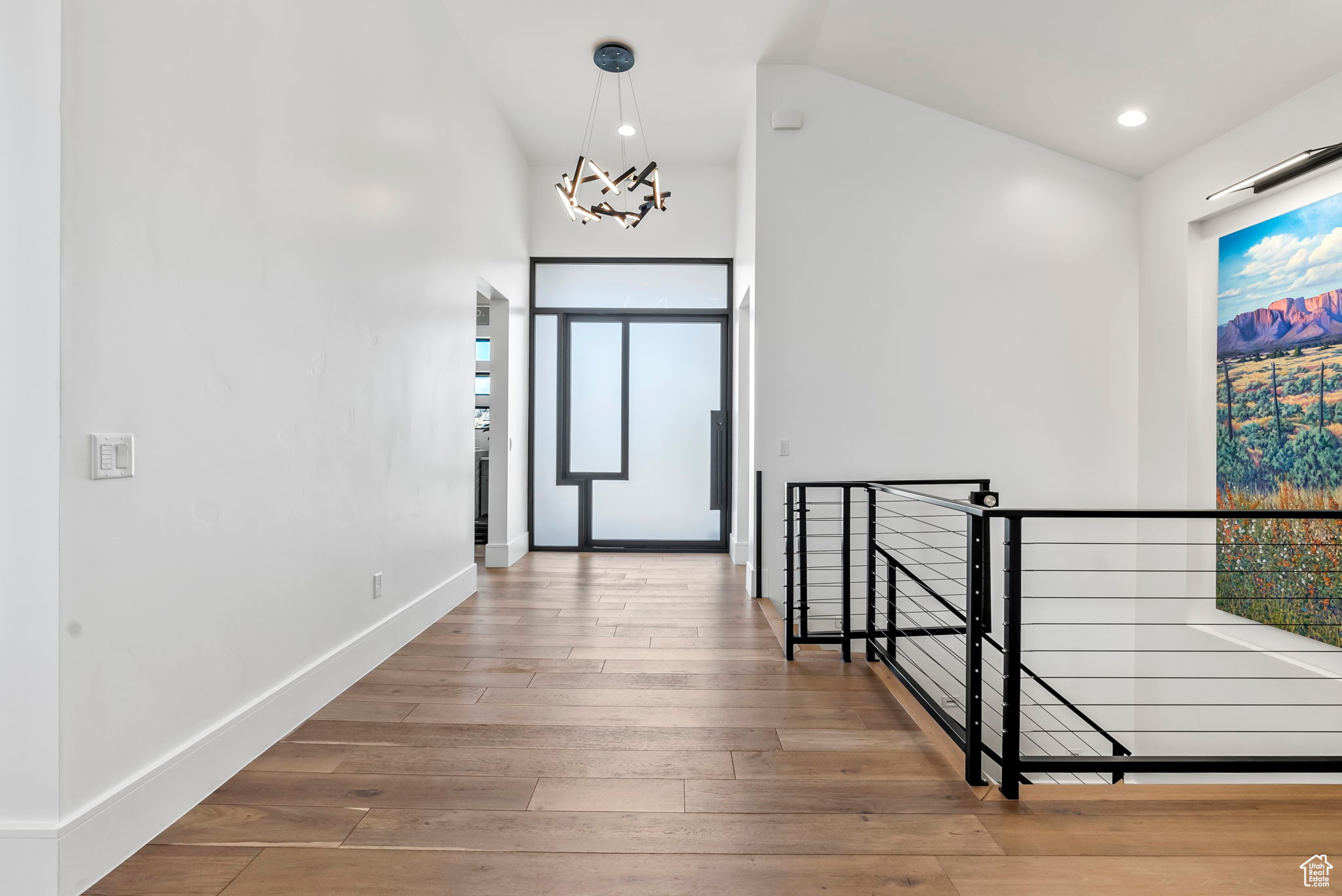 Corridor featuring lofted ceiling, hardwood / wood-style flooring, and a notable chandelier