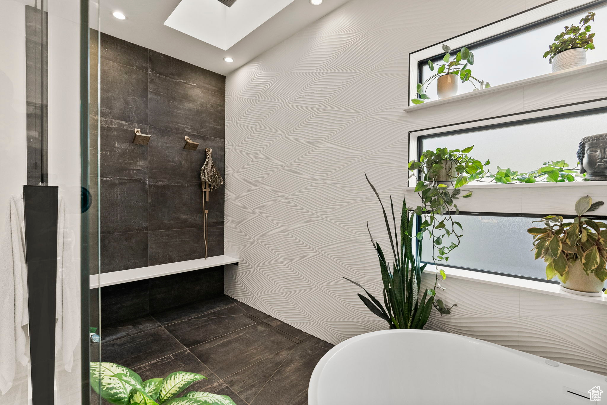 Bathroom with a skylight, tile walls, and a bathing tub