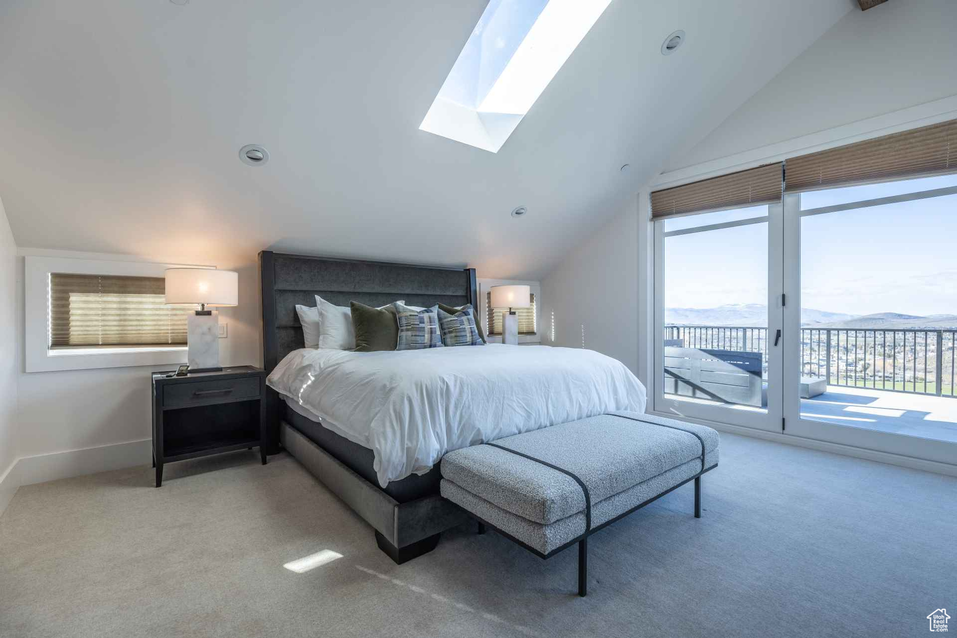 Carpeted bedroom featuring vaulted ceiling with skylight, a mountain view, and access to outside