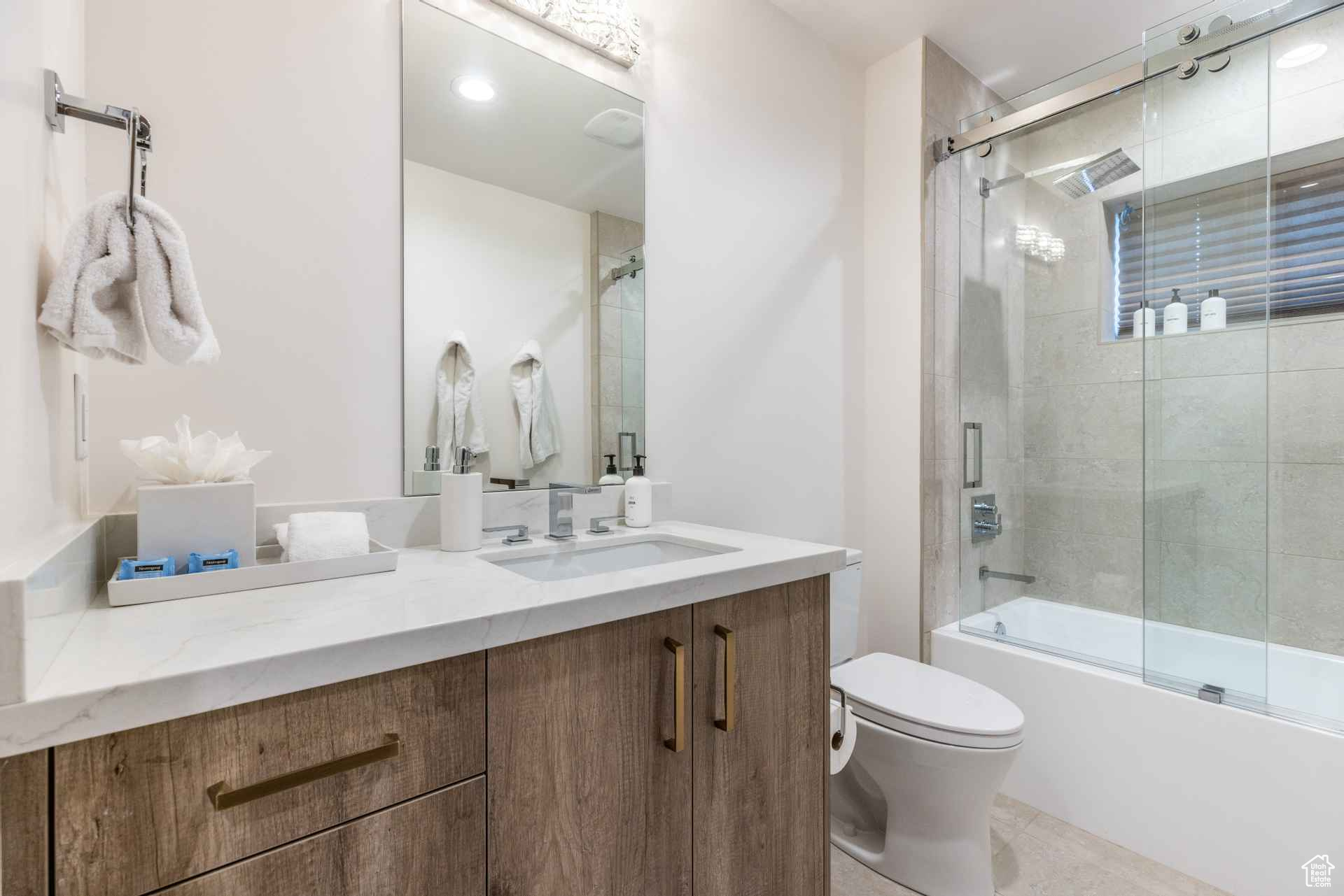 Full bathroom with vanity, enclosed tub / shower combo, and toilet