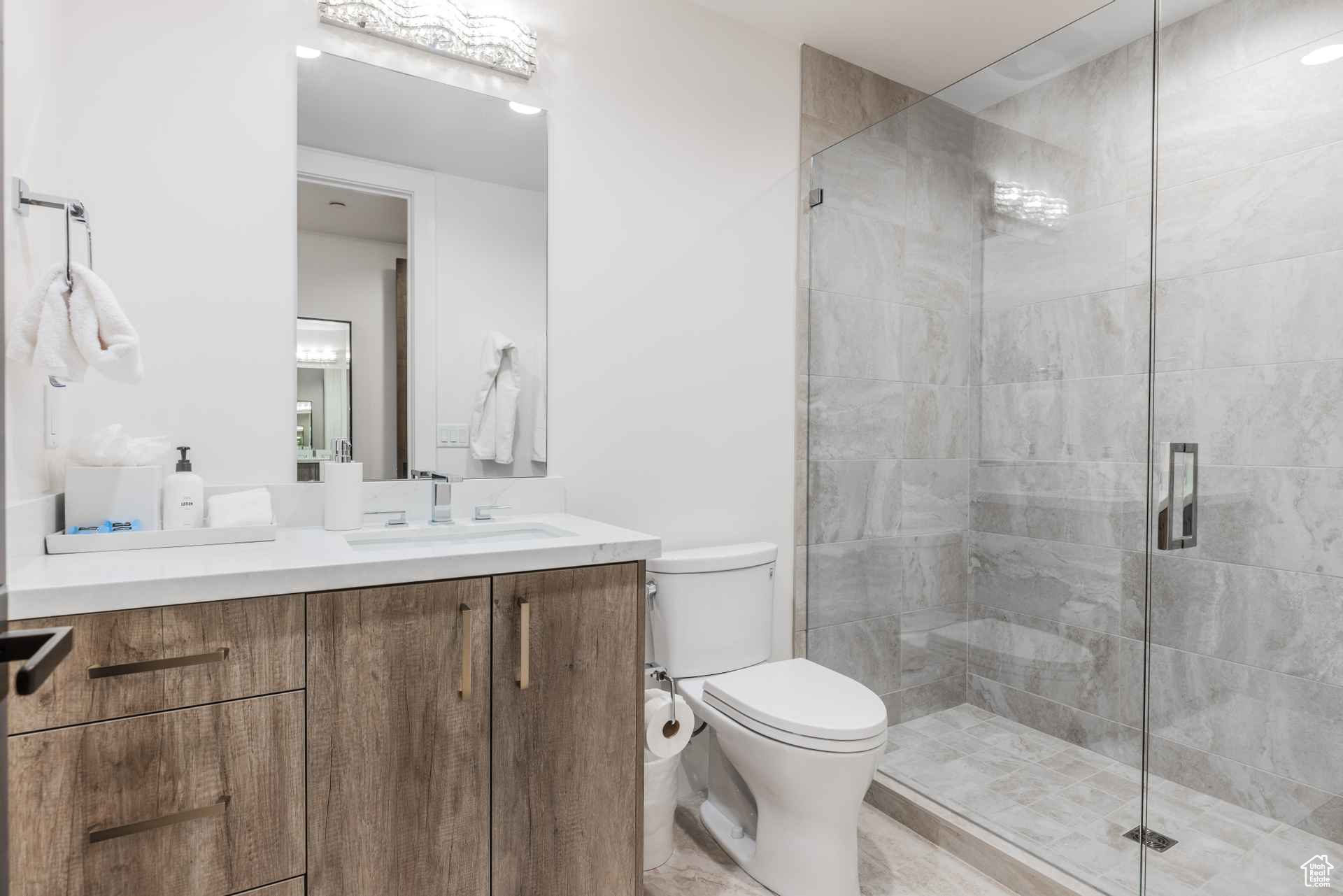 Bathroom with an enclosed shower, vanity, and toilet