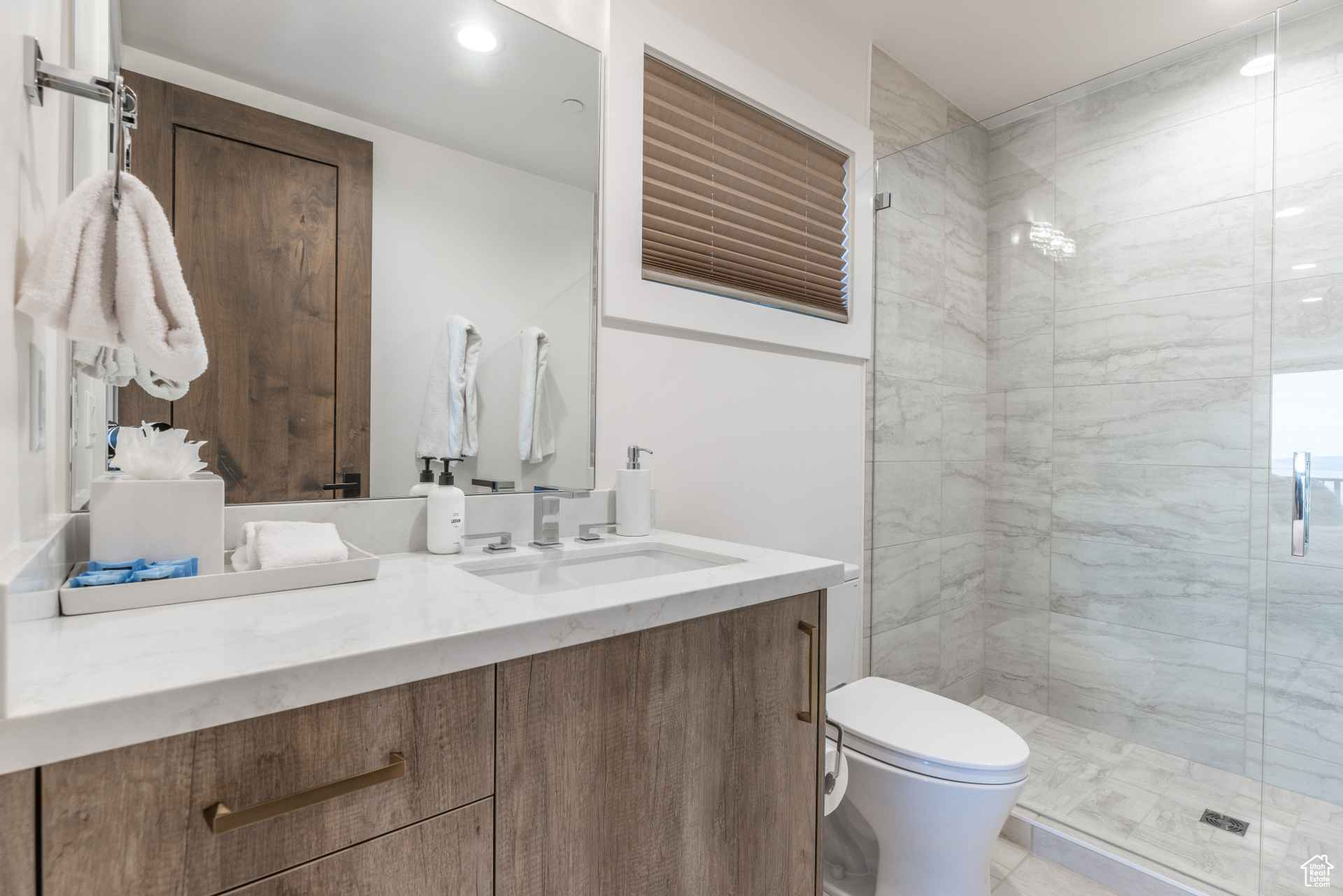 Bathroom featuring walk in shower, vanity, and toilet