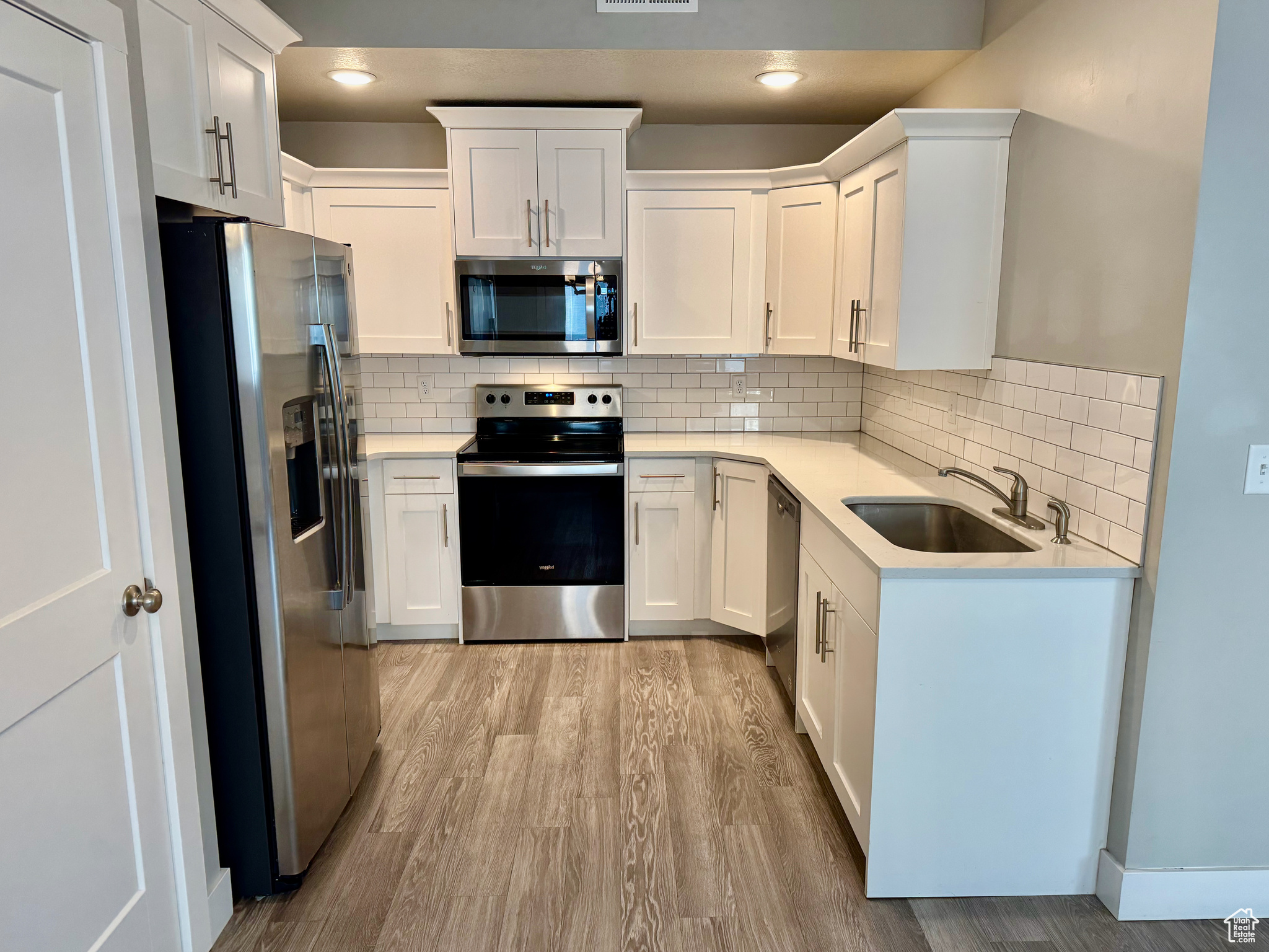 Kitchen with white cabinets, sink, appliances with stainless steel finishes, and tasteful backsplash