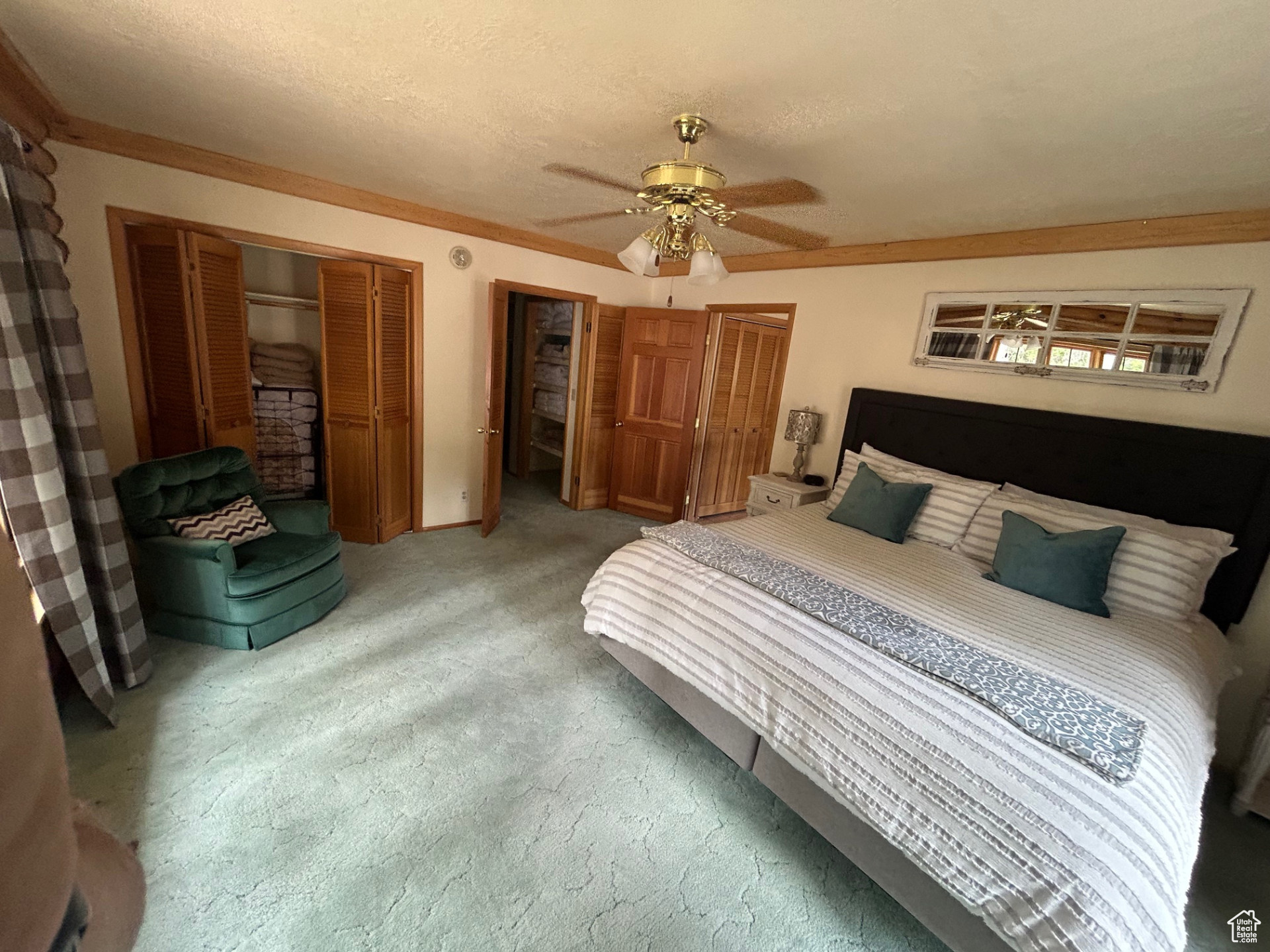 Carpeted bedroom featuring ceiling fan, a closet, and a textured ceiling