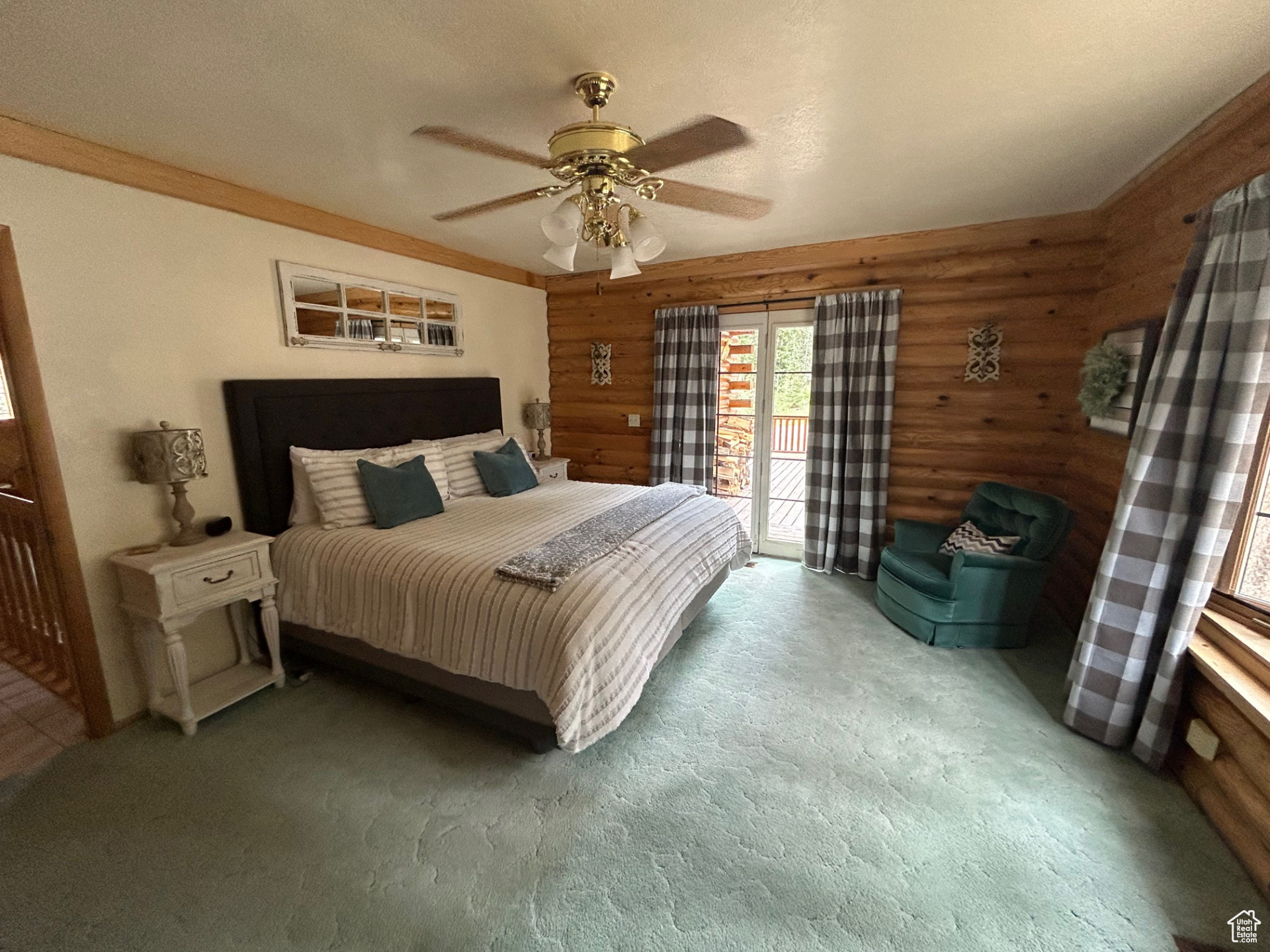 Carpeted bedroom featuring ceiling fan, rustic walls, and access to outside