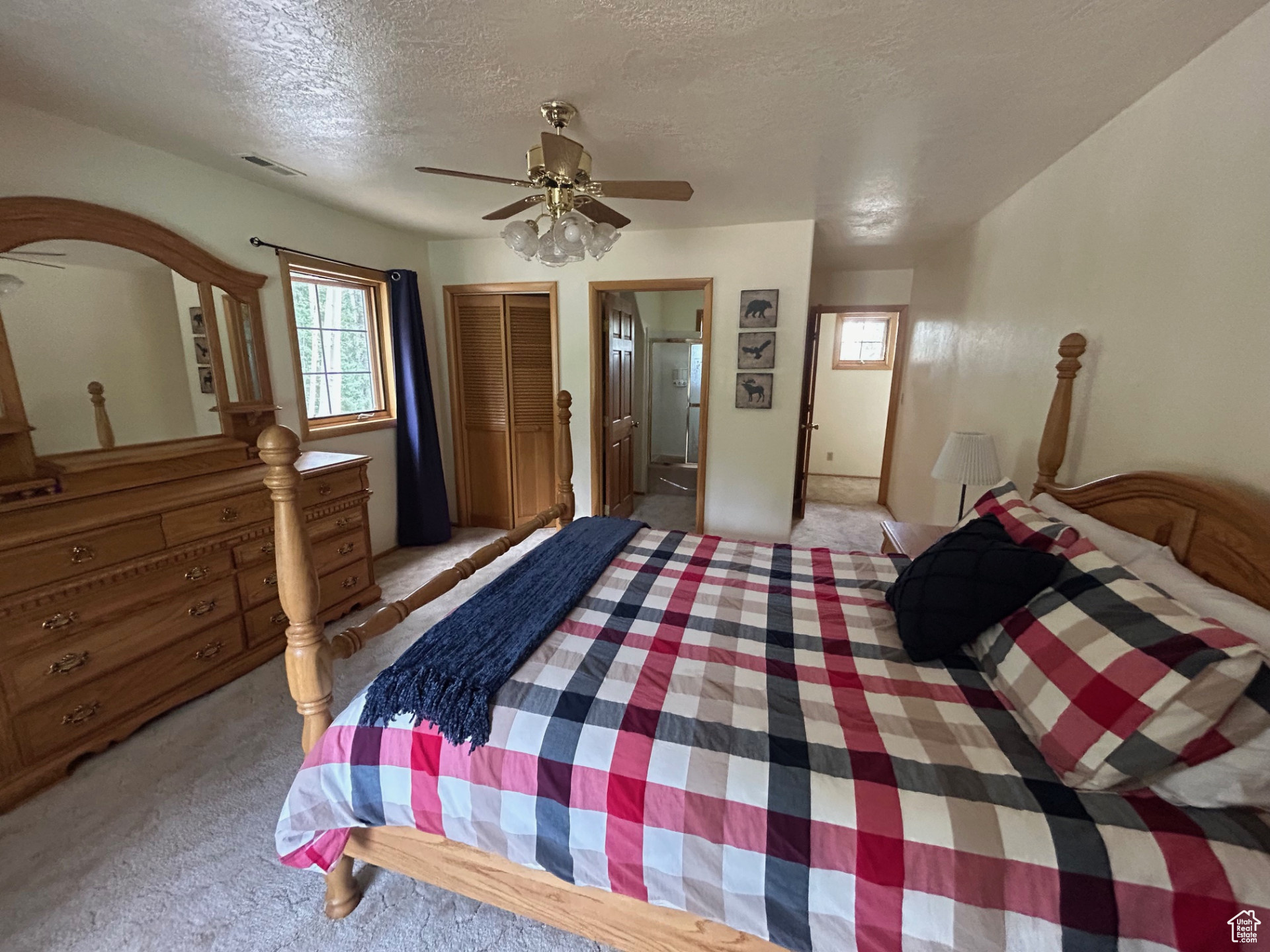 Carpeted bedroom with ceiling fan, a textured ceiling, connected bathroom, and a closet