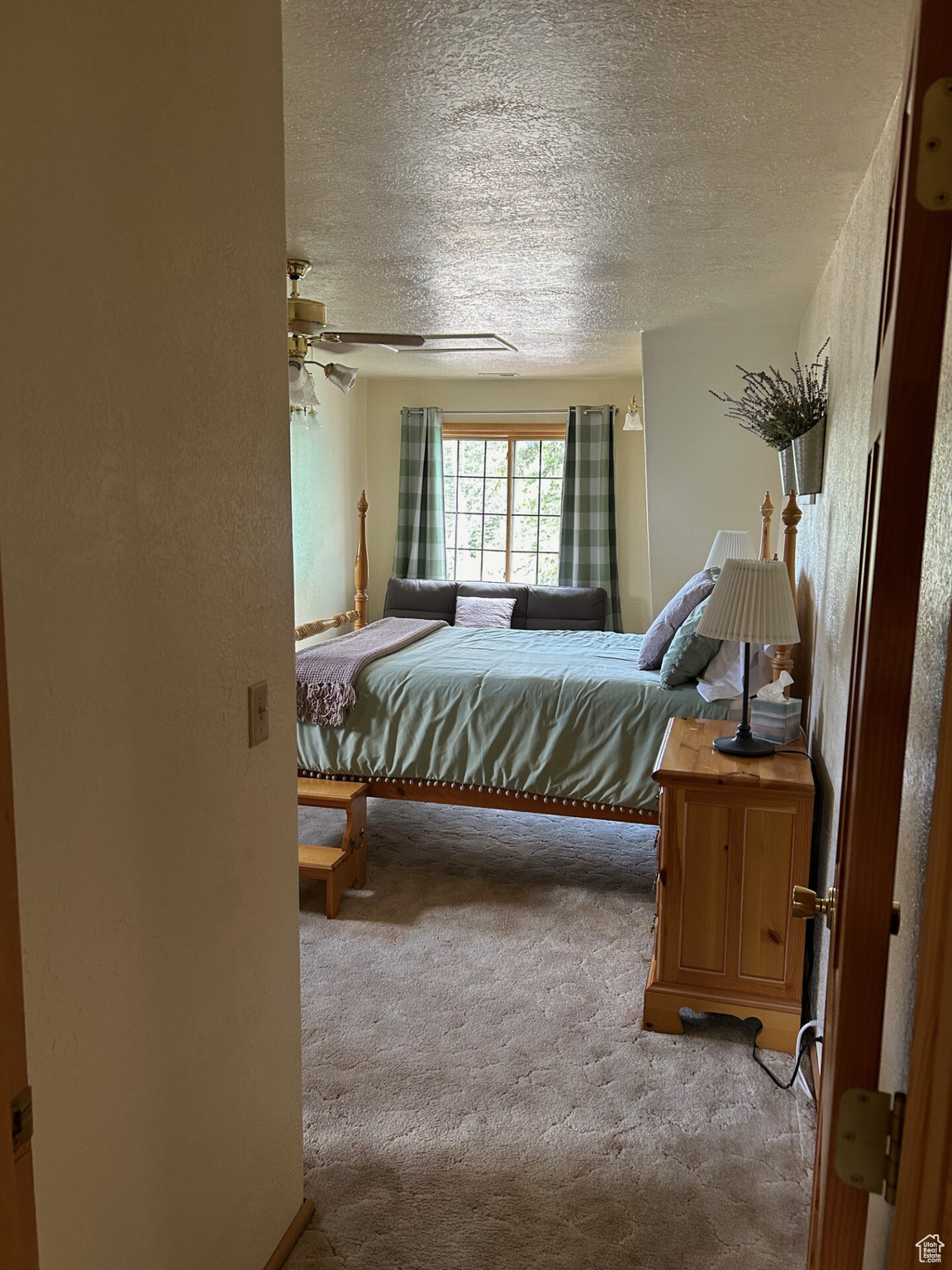 Carpeted bedroom featuring ceiling fan and a textured ceiling