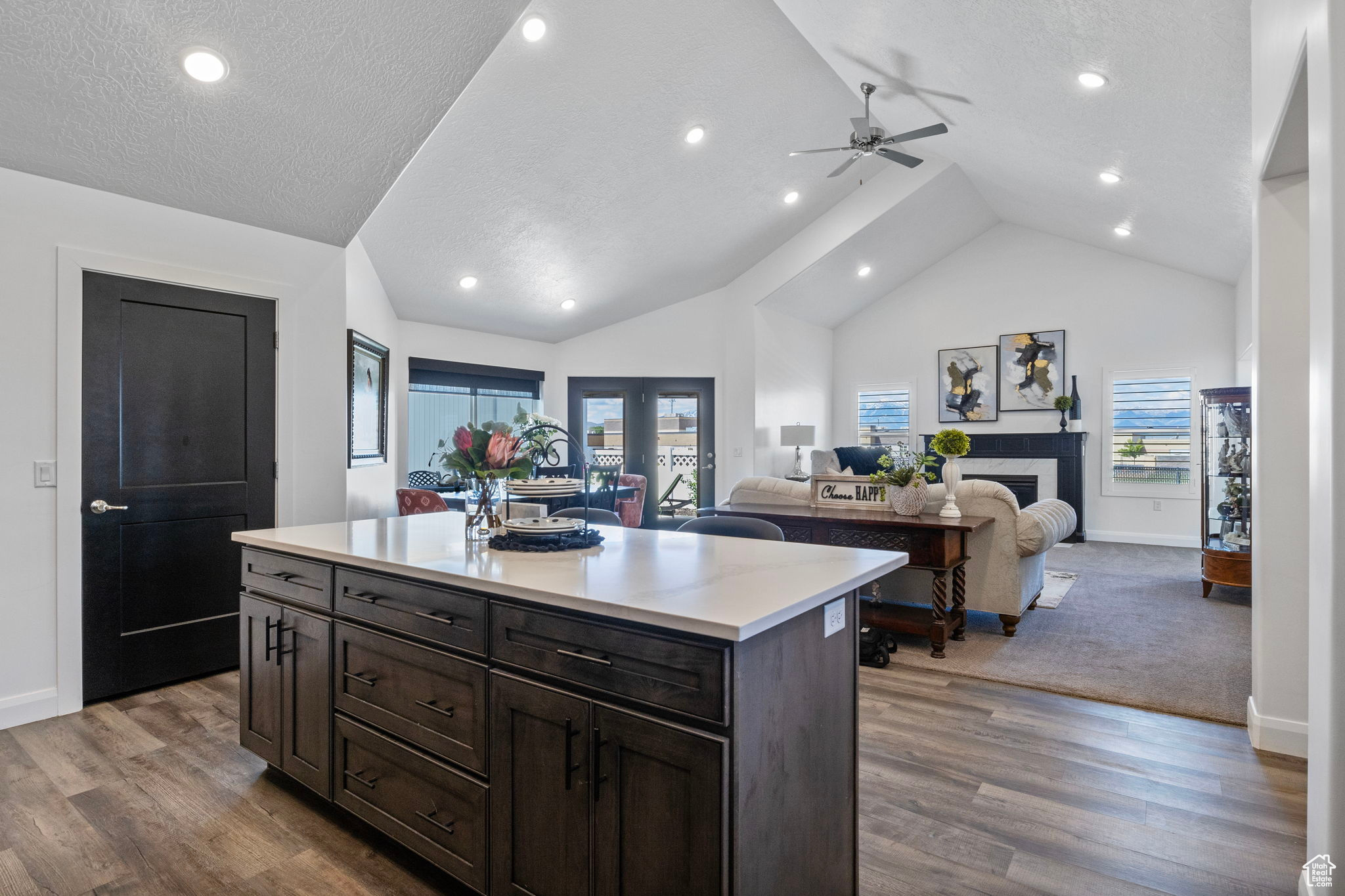 Kitchen with hardwood / wood-style floors, a kitchen island, a textured ceiling, and a high end fireplace