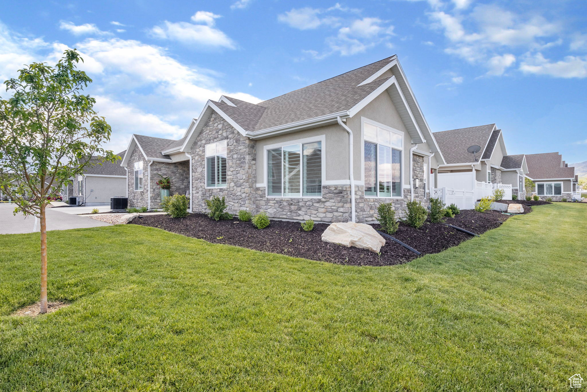 View of front of property featuring central air condition unit, a front lawn, and a garage